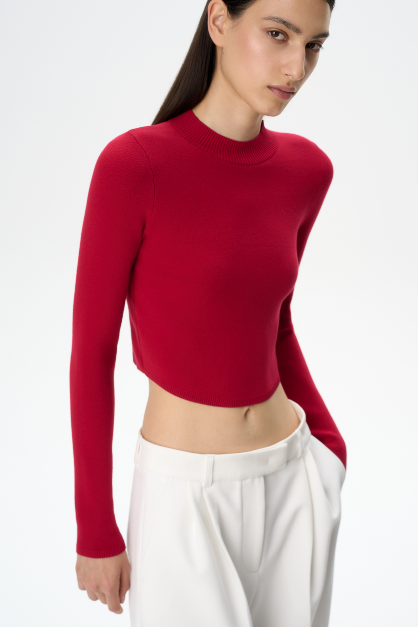 Трикотажный кроп-топ из вискозы с длинным рукавом, круглым вырезом горловины и фигурным низом. Края изделия выполнены в рубчик.