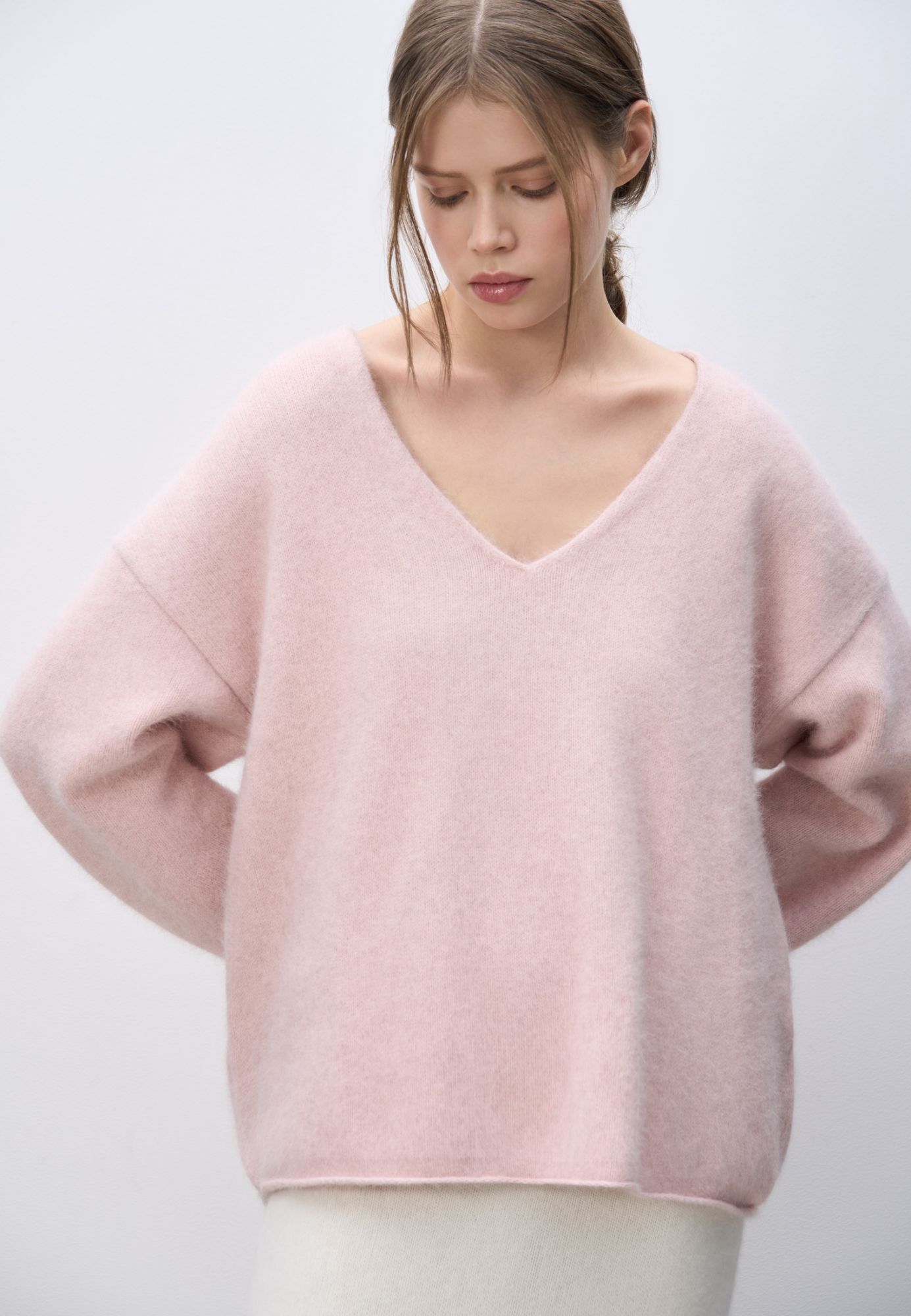 Объемный трикотажный джемпер из пуха лисы. Модель с глубоким V-образным вырезом горловины, спущенной линией плеч, длинными широкими рукавами и валиками по низу. Дополнить образ можно юбкой.