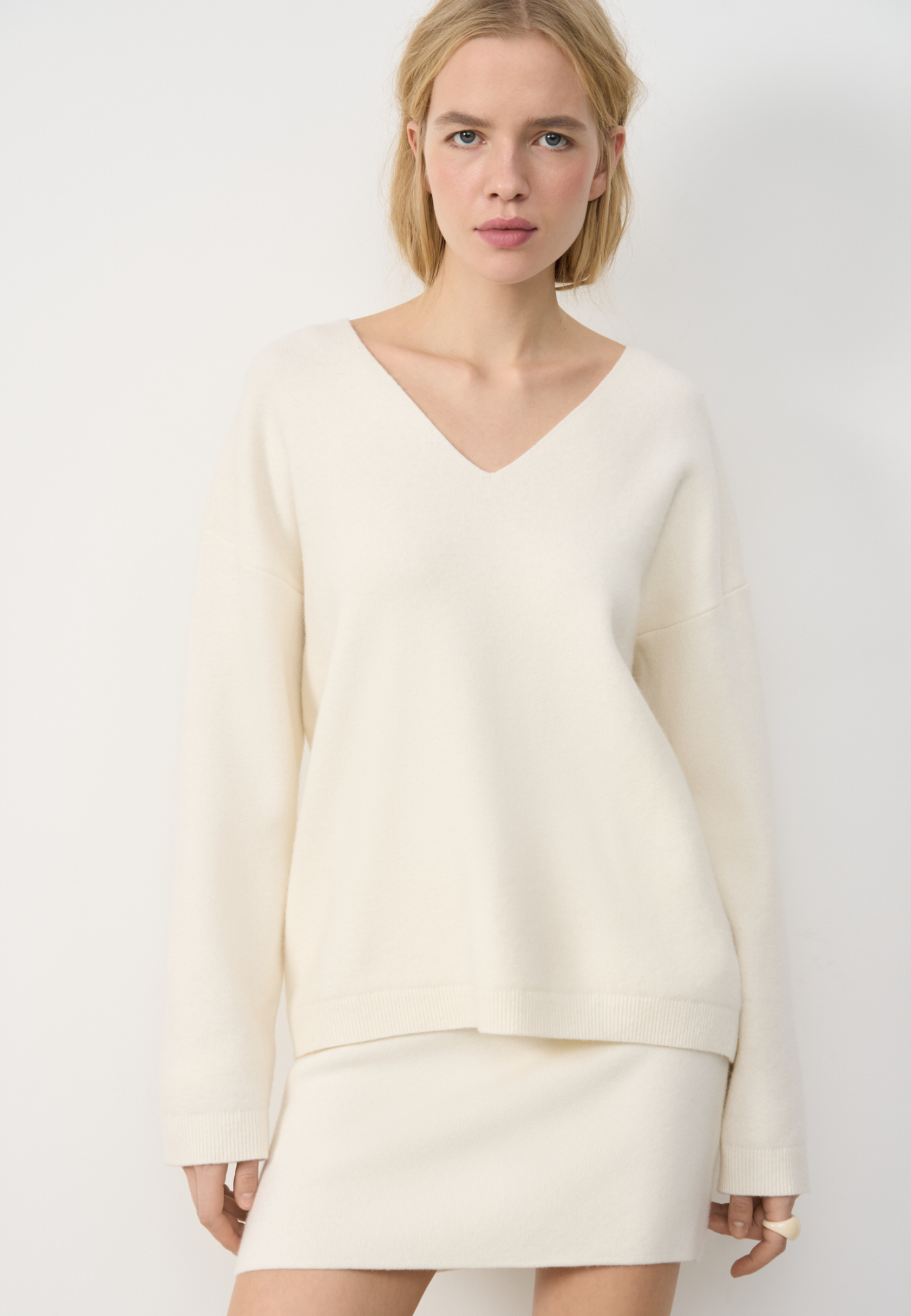 Трикотажный джемпер из шерсти с добавлением кашемира. Модель свободного силуэта со спущенной линией плеч и V-образным вырезом горловины. Манжеты рукавов и низ изделия выполнены в рубчик.