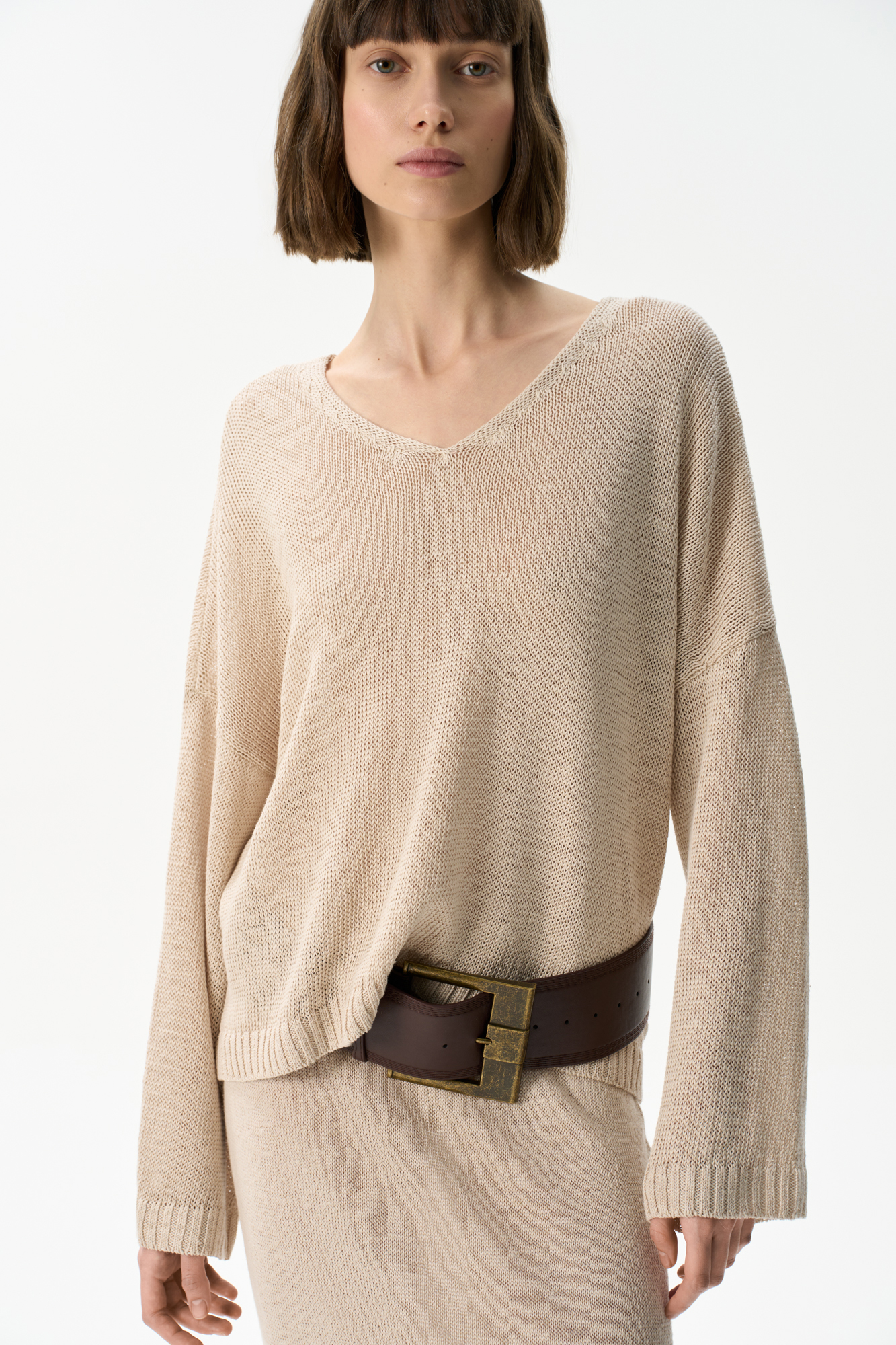 Трикотажный джемпер из 100% льна с V-образным вырезом. Модель прямого силуэта с длинным рукавом и удлиненной спинкой. Края изделия выполнены в рубчик.