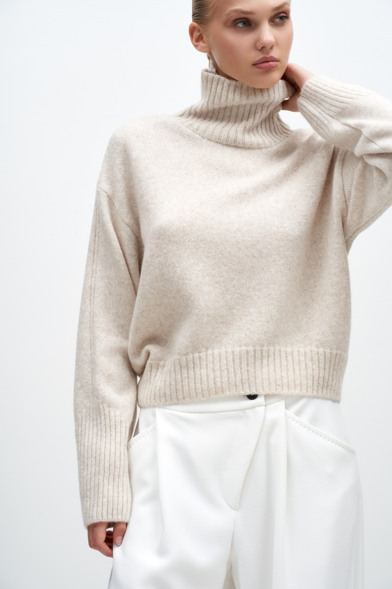 Джемпер из шерсти мериноса экстрафайн. Модель свободного силуэта с высоким воротом. Воротник, манжеты и низ изделия выполнены в широкий рубчик. Рубчик на манжетах образует асимметричный узор и с внешней стороны рукава продолжается до плеча. 