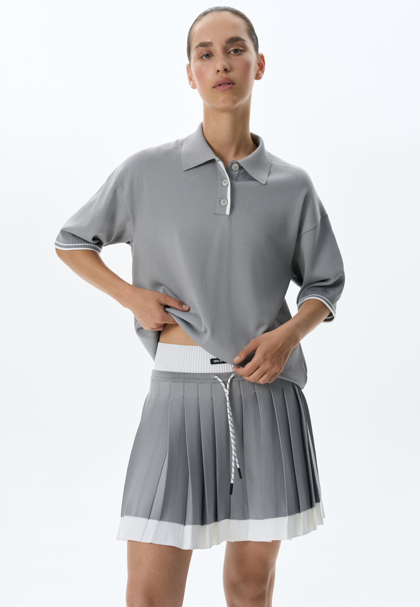 Трикотажная футболка поло из вискозы. Модель прямого силуэта, со спущенной линией плеч, короткими рукавами, отложным воротником-поло и планкой с тремя пуговицами. Рукава и нижний край изделия декорированы кантом контрастного цвета.