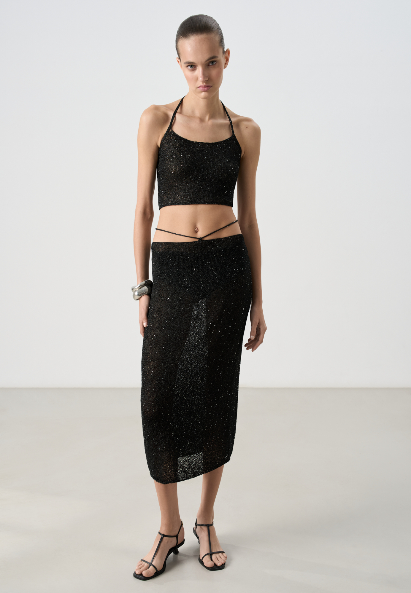 Трикотажная юбка длины миди из хлопка с добавлением вискозы. Изделие декорировано мелкими пайетками. Модель прямого кроя с акцентной деталью в виде тонкого пояса. Без подкладки.