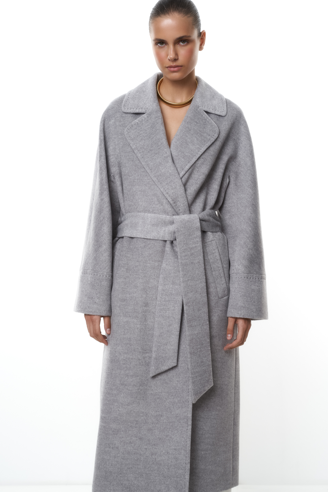 Длинное шерстяное пальто на запах на подкладке без застежки, с поясом из основной ткани. V-образный вырез с лацканами. Два кармана в боковых швах. <br />
