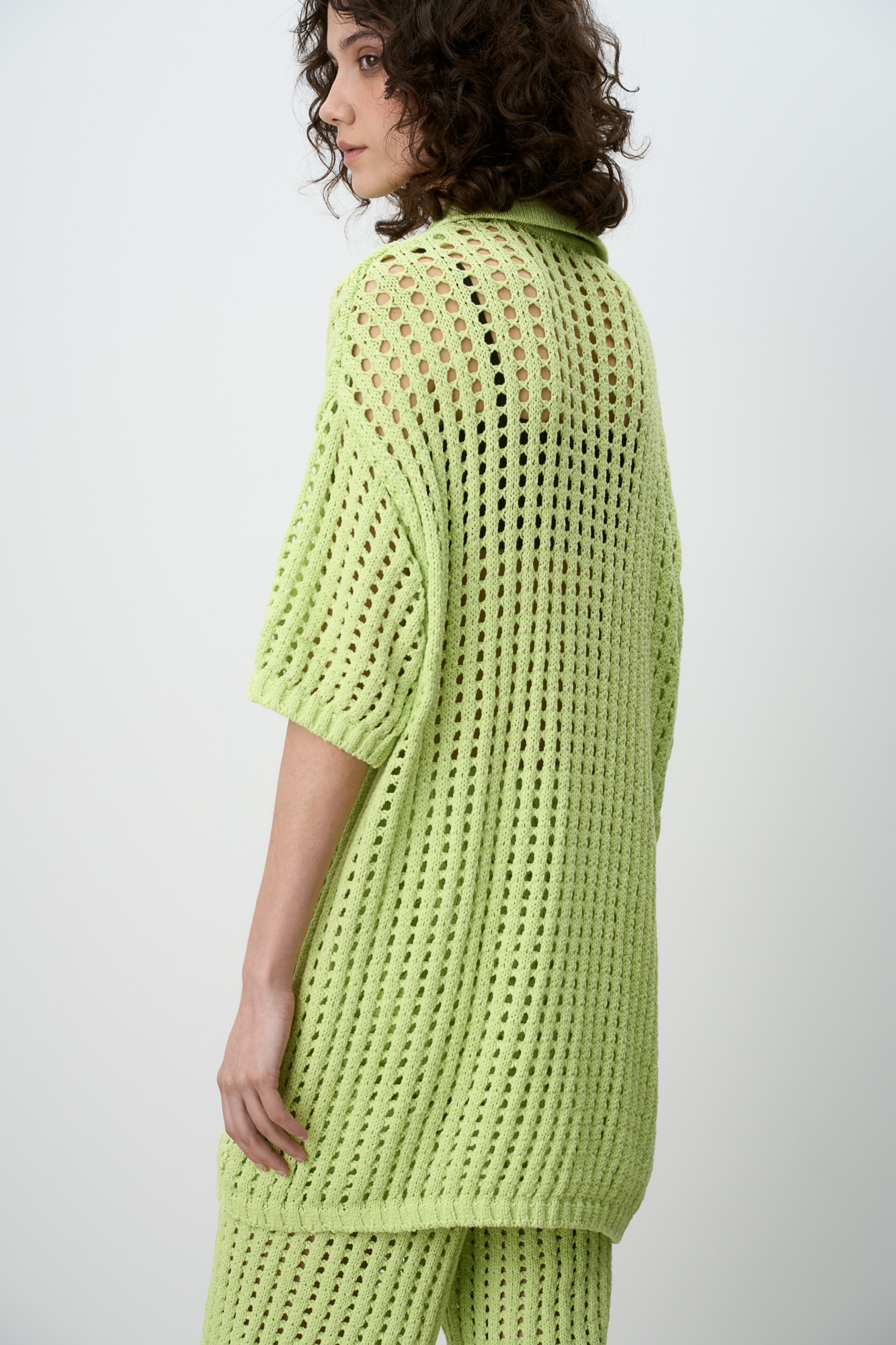 Трикотажная ажурная футболка из 100% хлопка. Модель со спущенным рукавом и воротником-поло. Дополнить образ можно шортами в таком же стиле.