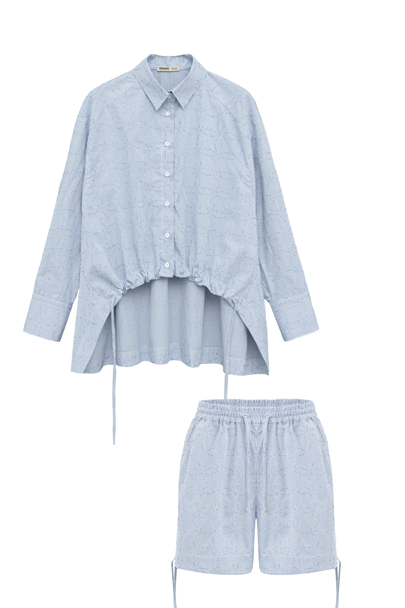 Принтованный костюм из 100% хлопка, состоящий из рубашки и шорт. Рубашка свободного кроя, с длинными рукавами, классическим отложным воротником и кулиской по низу изделия. Короткие шорты с карманами, широким поясом на кулиске и завязками по бокам.