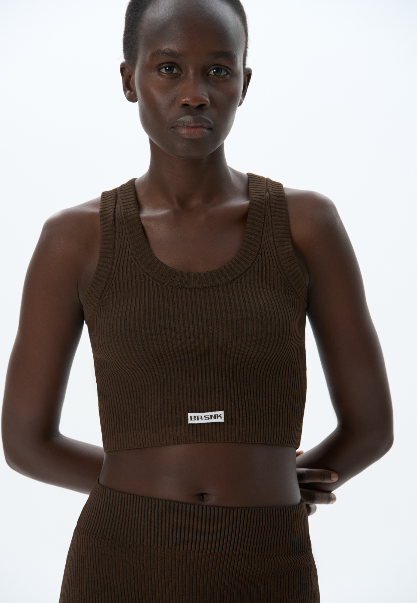 Трикотажный короткий топ из вискозы. Модель по фигуре, без рукавов и U-вырезом головины. Изделие выполнено в рубчик и декорирован брендированным жаккардом спереди.