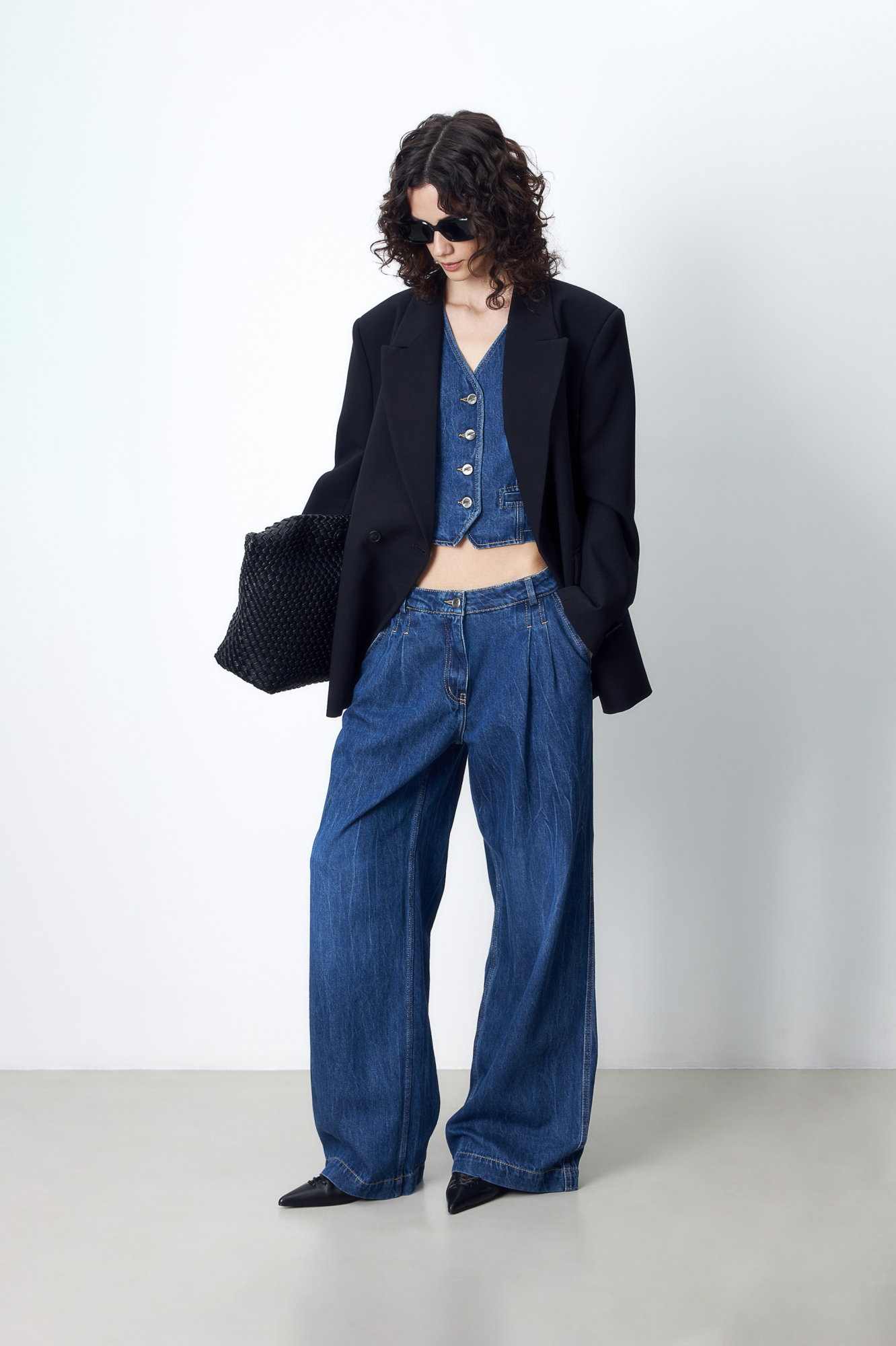 Джинсовый костюм из 100% хлопка, состоящий из джинс и жилета. Широкие джинсы прямого силуэта, со средней посадкой, застежкой на молнию и пуговицу, шлевки на поясе для ремня. Приталенный жилет с имитацией карманов и V-образным вырезом. Застежка на металлические пуговицы.