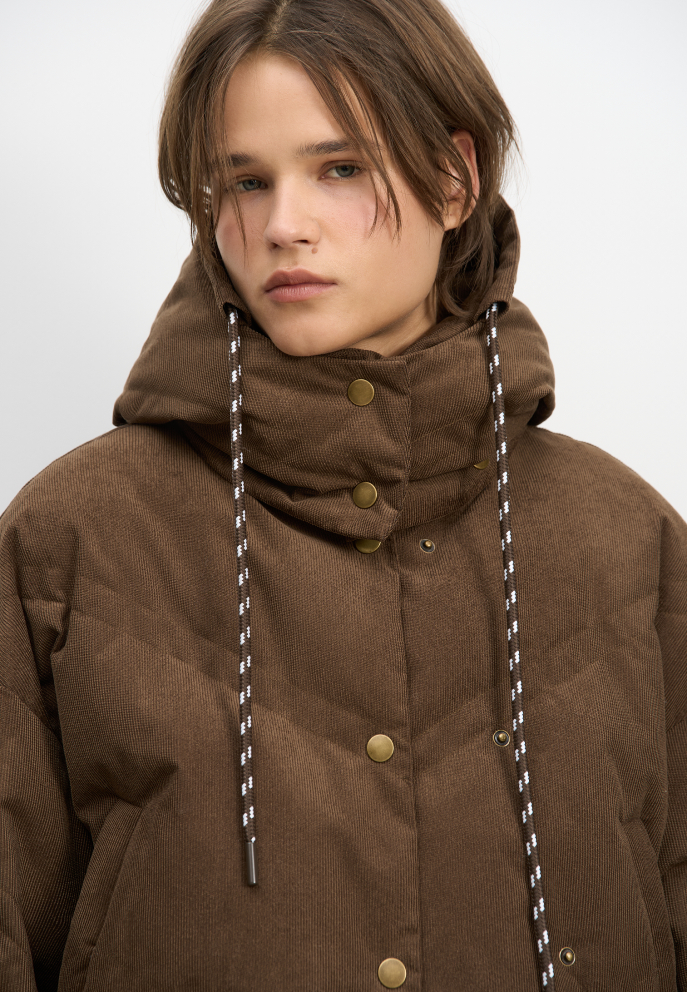 Пуховик с воротником-стойкой, съемным капюшоном и графичной стежкой с двойной отстрочкой. Модель имеет два варианта застежки на металлические кнопки. Низ изделия выполнен на кулиске.