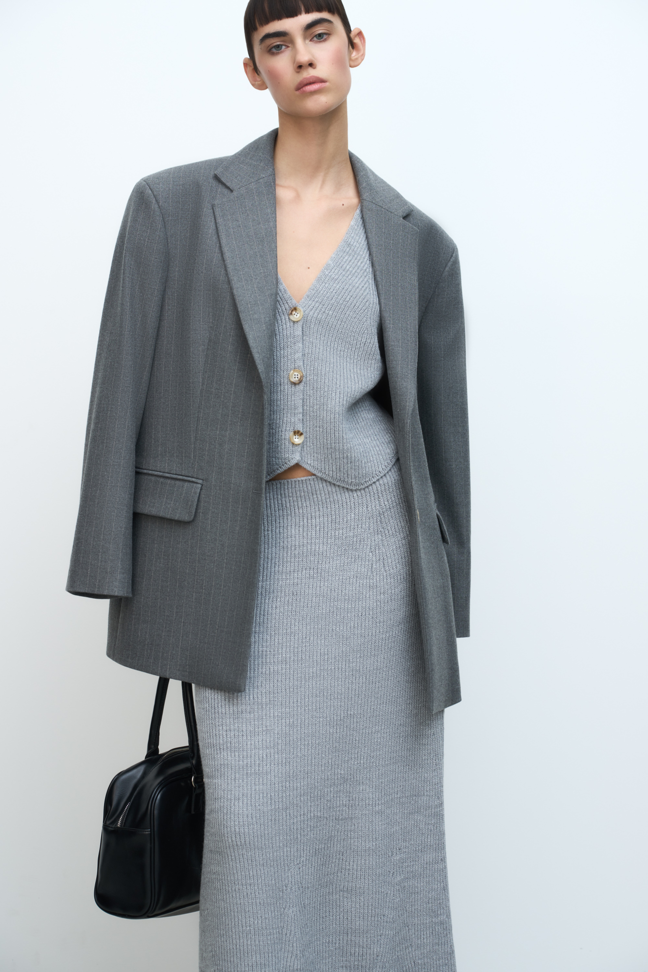 Трикотажный жилет из шерсти. Модель прямого кроя с глубоким V-образным вырезом и застежкой на пуговицы. Дополнить образ можно юбкой в таком же стиле.