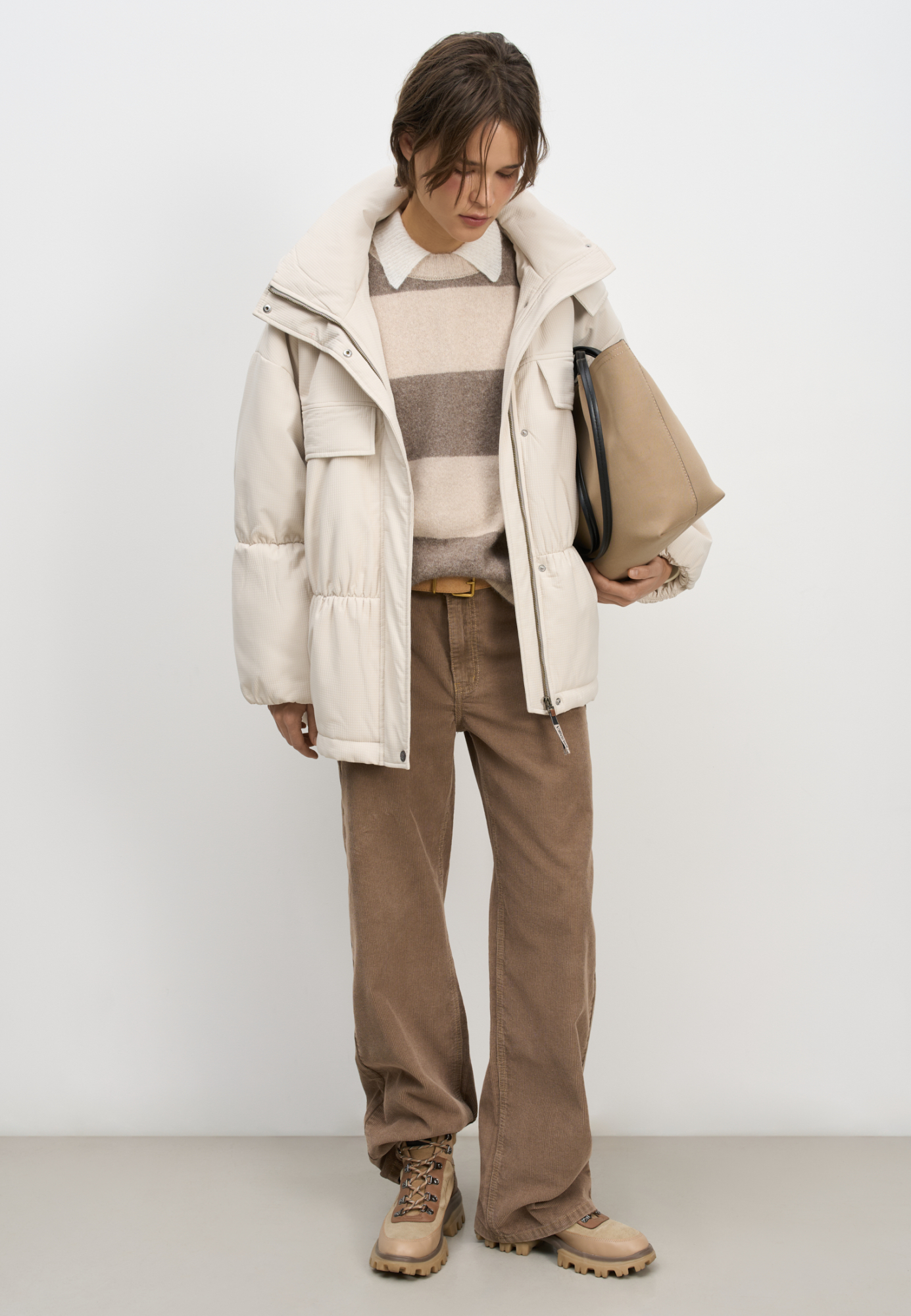 Длинная куртка на синтепоне из текстурной ткани. Модель свободного силуэта со спущенной линией плеча, накладными и боковыми карманами, воротником-стойкой и капюшоном. Изделие на подкладке. Застежка на молнию под планкой с кнопками.