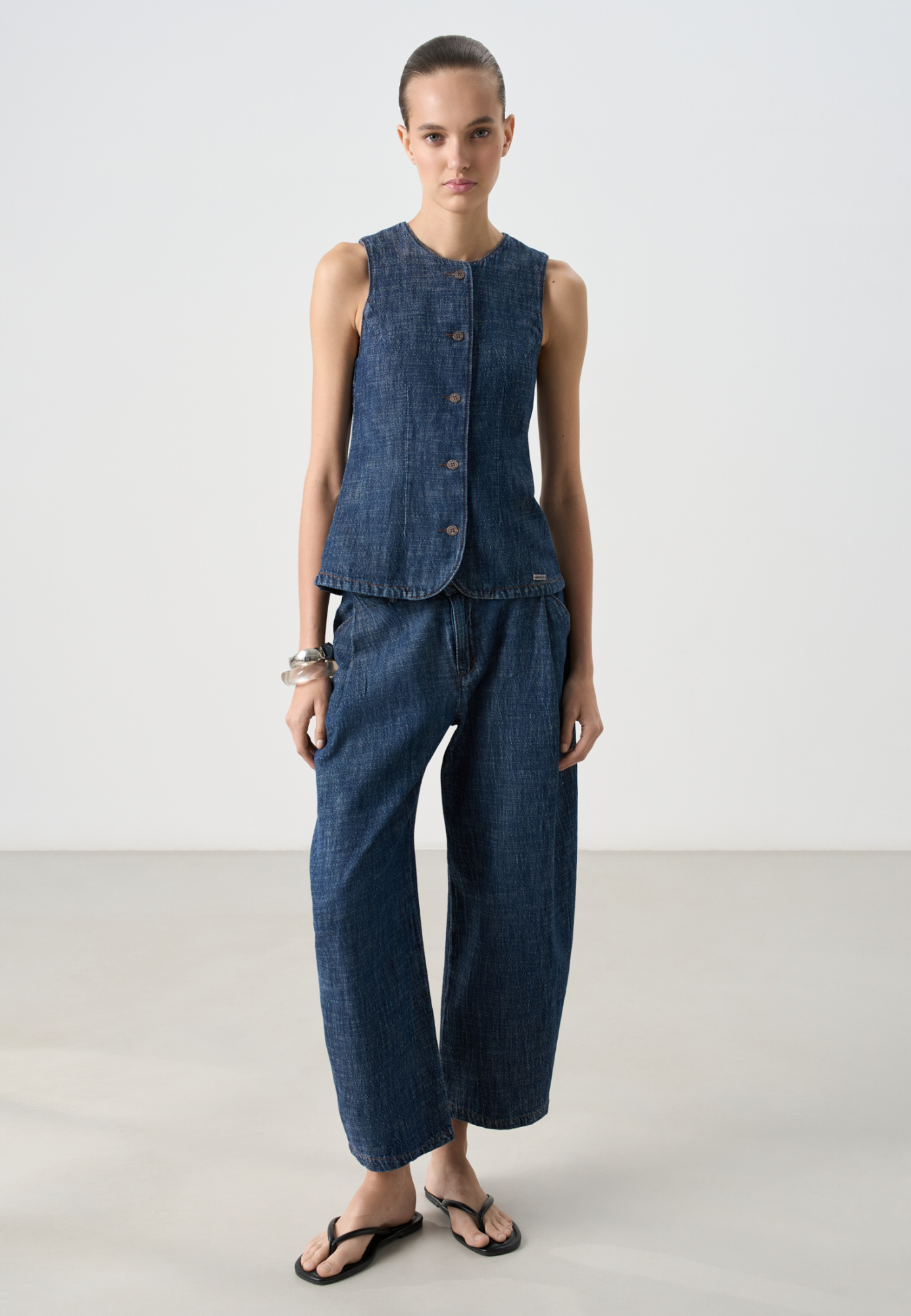 Джинсы из 100% хлопка. Модель прямого кроя, с низкой посадкой, акцентными защипами на талии, шлевками на поясе для ремня и застежкой на молнию и пуговицу.