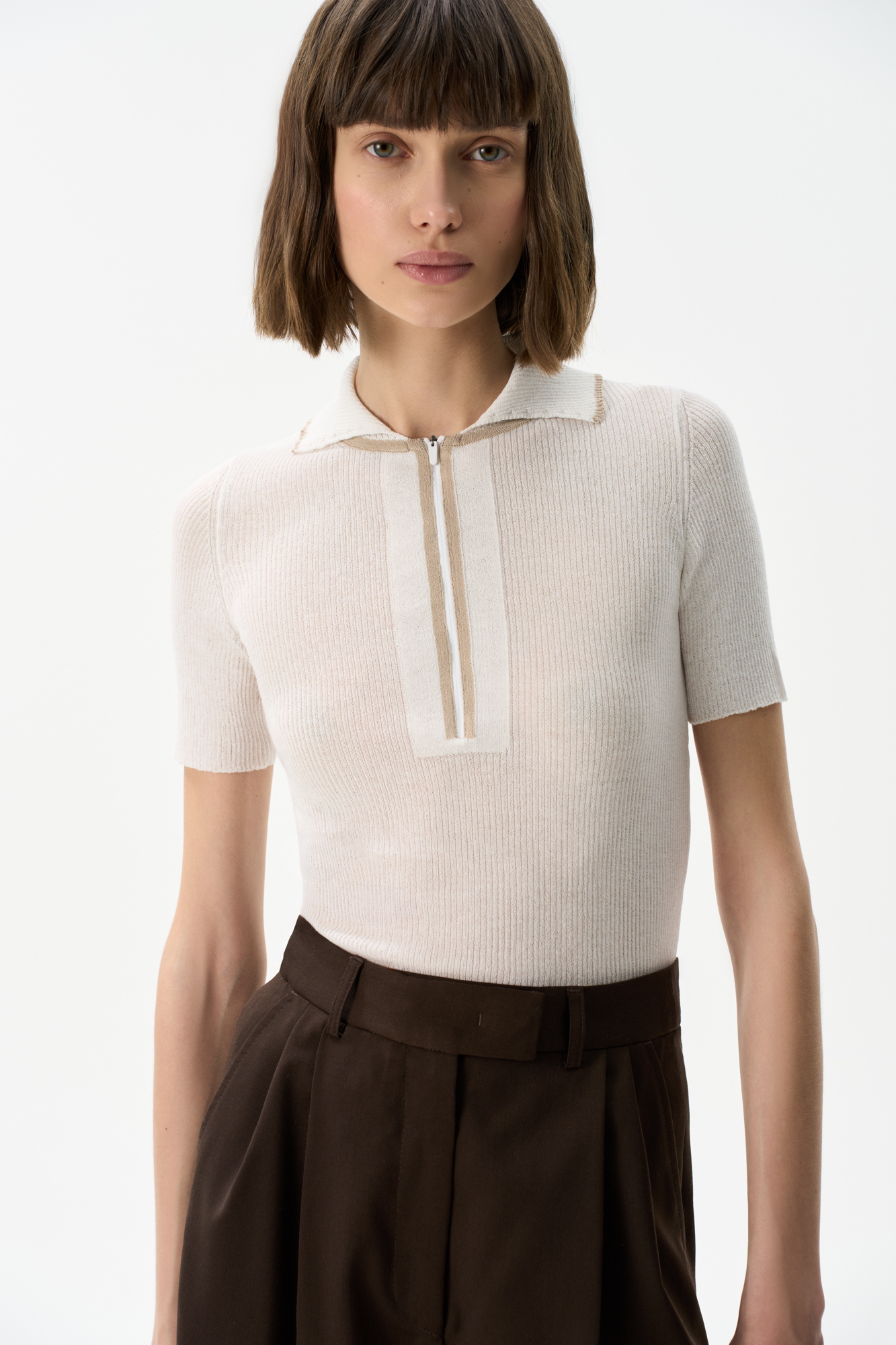 Трикотажная футболка-поло из 100% хлопка. Модель приталенного силуэта, с коротким рукавом, отложным воротником и застежкой на потайную молнию. Изделие декорировано бежевой отделкой на воротнике и вдоль планки. 