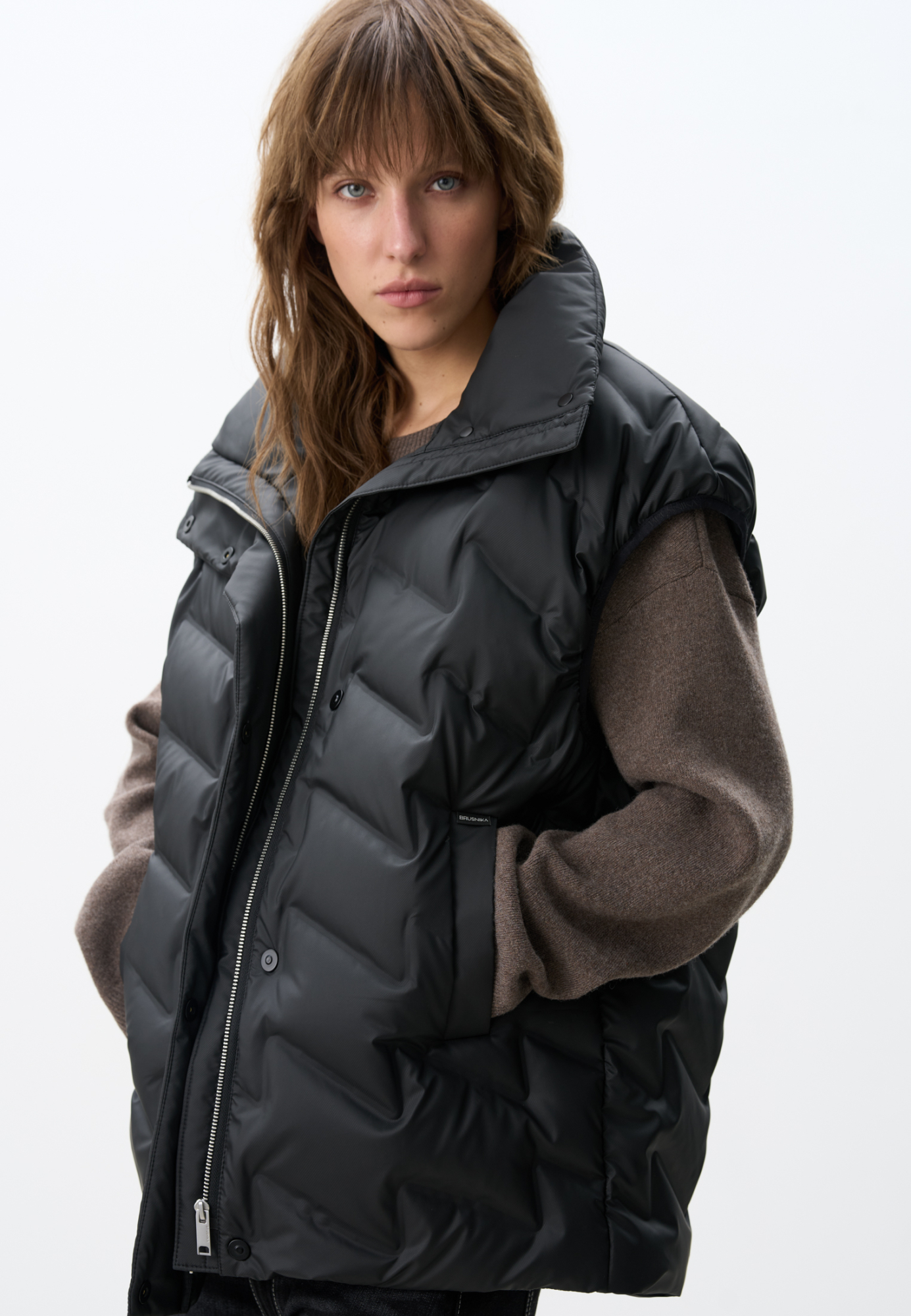 Объемный стеганый жилет на пуху. Модель прямого кроя, с воротником стойкой и боковыми карманами. Застежка на молнию и кнопки под планкой.