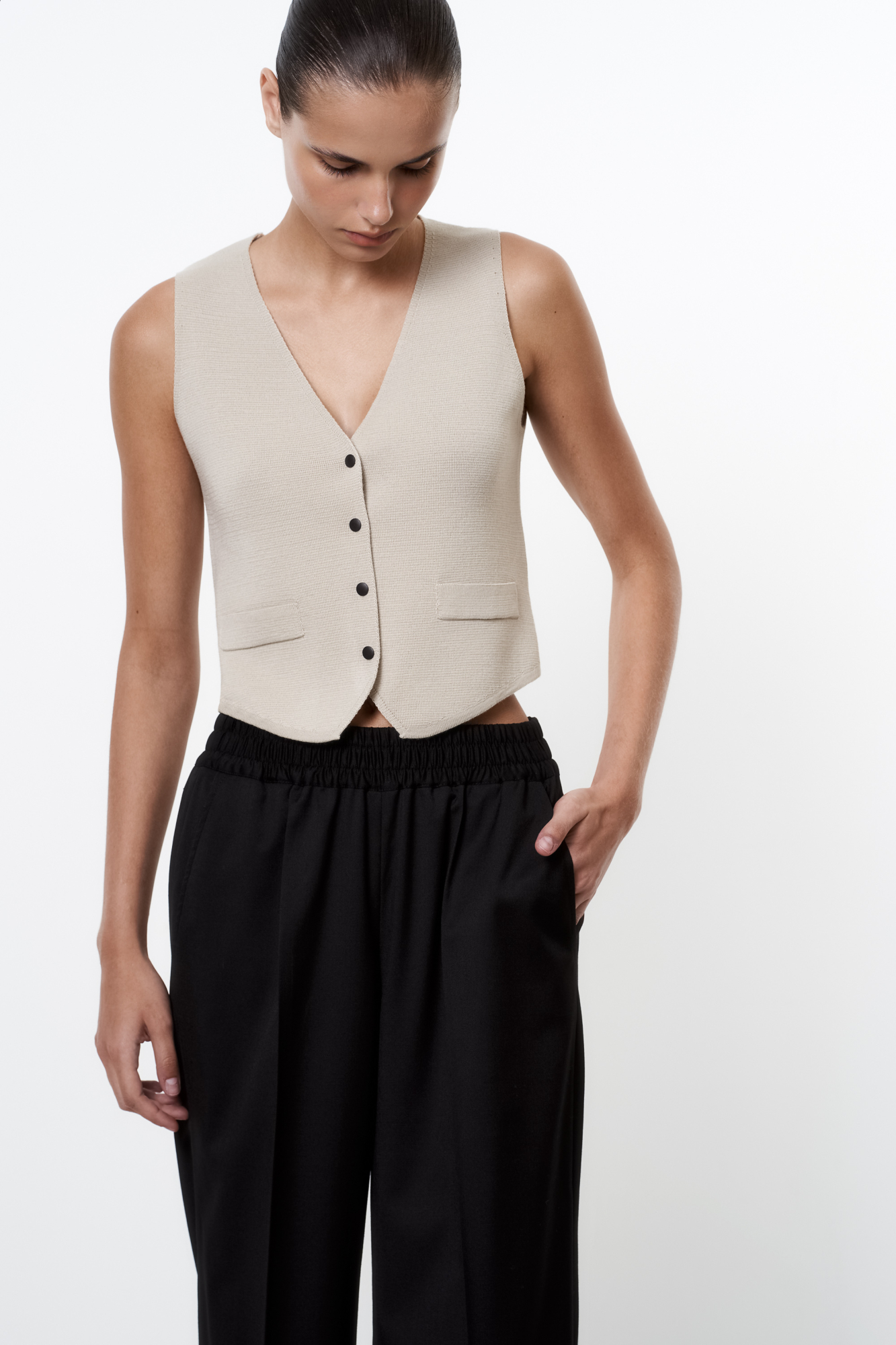 Трикотажный однобортный жилет из шерсти мериноса экстрафайн. Модель прямого кроя с имитацией карманов с клапанами и V-образным вырезом. Застежка на кнопки. Изделие без подкладки. Дополнить образ можно жакетом, бомбером, брюками или юбкой.