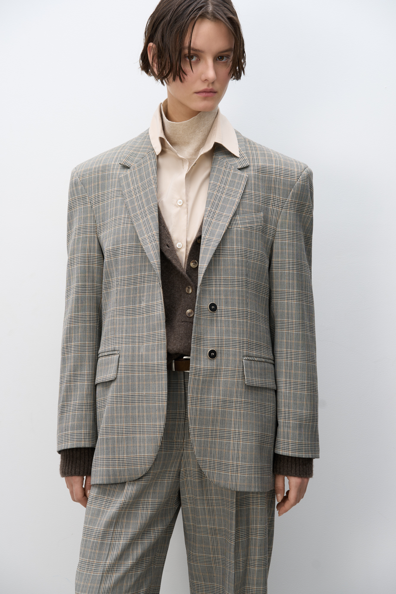 Однобортный жакет в клетку гленчек. Модель прямого кроя с лацканами, боковыми карманами с клапанами и нагрудным карманом. Застежка на две пуговицы. Изделие выполнено на подкладке.