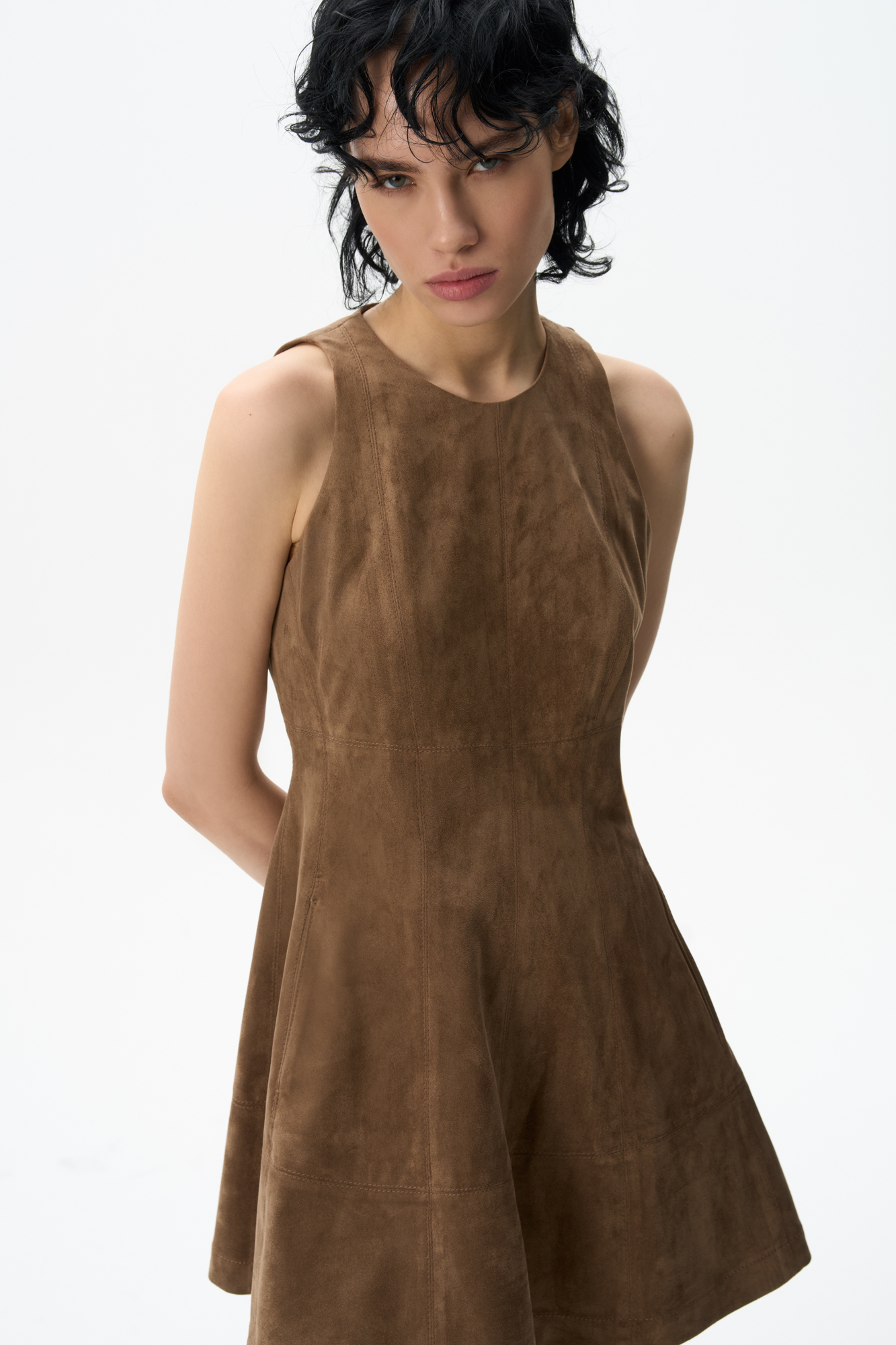 Платье длины мини из ткани с имитацией внешнего вида и свойств натуральной замши. Модель приталенного силуэта без рукавов, с круглым вырезом горловины и на широких бретельках. Застежка на молнию на спинке.