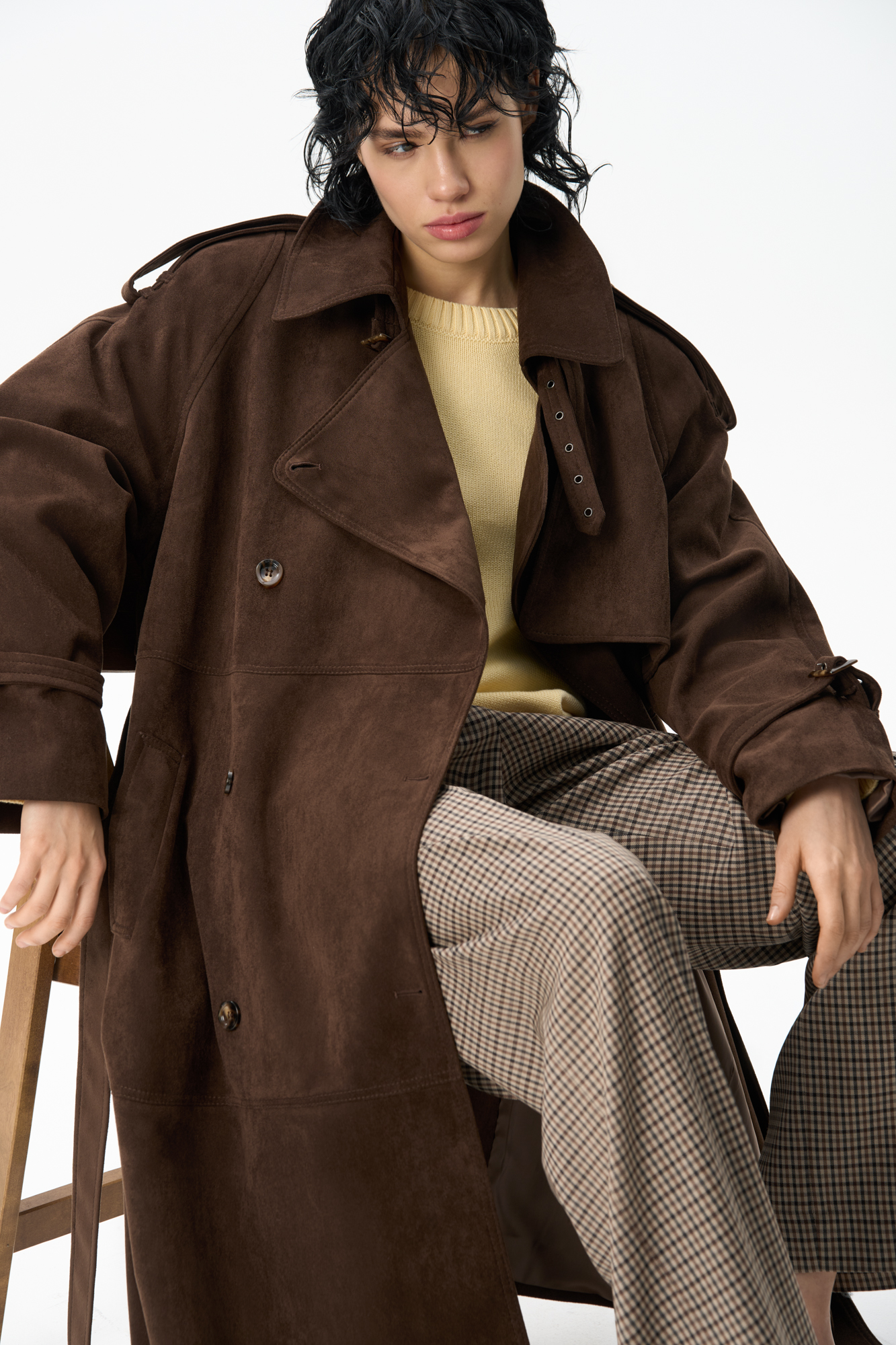 Двубортный длинный тренч, выполненный из ткани с имитацией внешнего вида и свойств натуральной замши. <br />
Модель с отложным воротником, отлетной кокеткой, патами на плечах и манжетах рукавов, карманами и шлевками на талии для ремня. Изделие выполнено на подкладке.