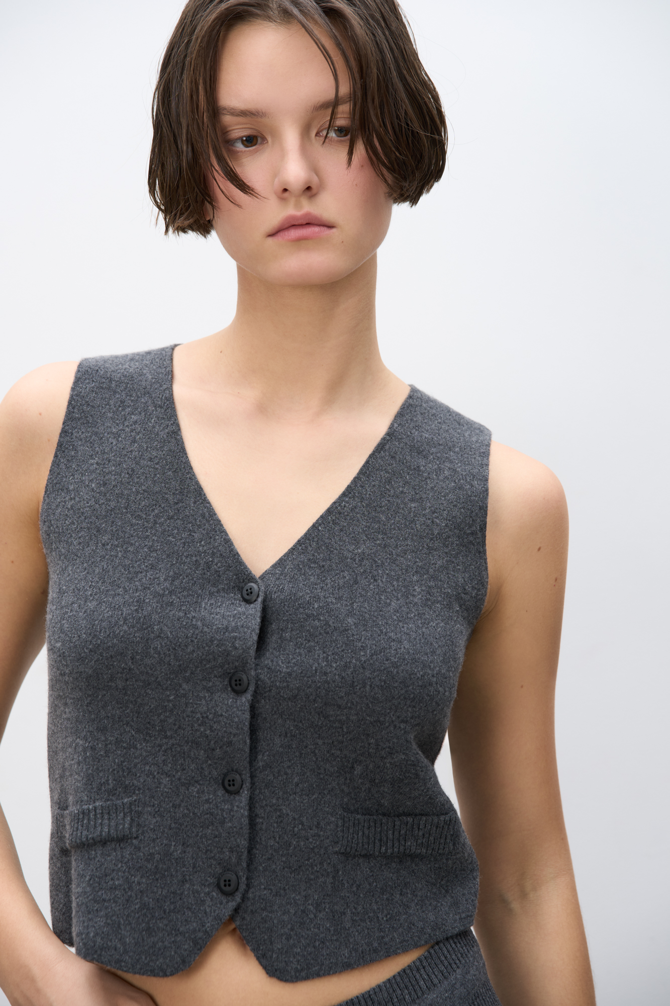 Трикотажный жилет из смесовой шерсти с кашемиром. Модель прямого кроя с V-образным вырезом и застежкой на пуговицы. Имитация карманов. Без подкладки.