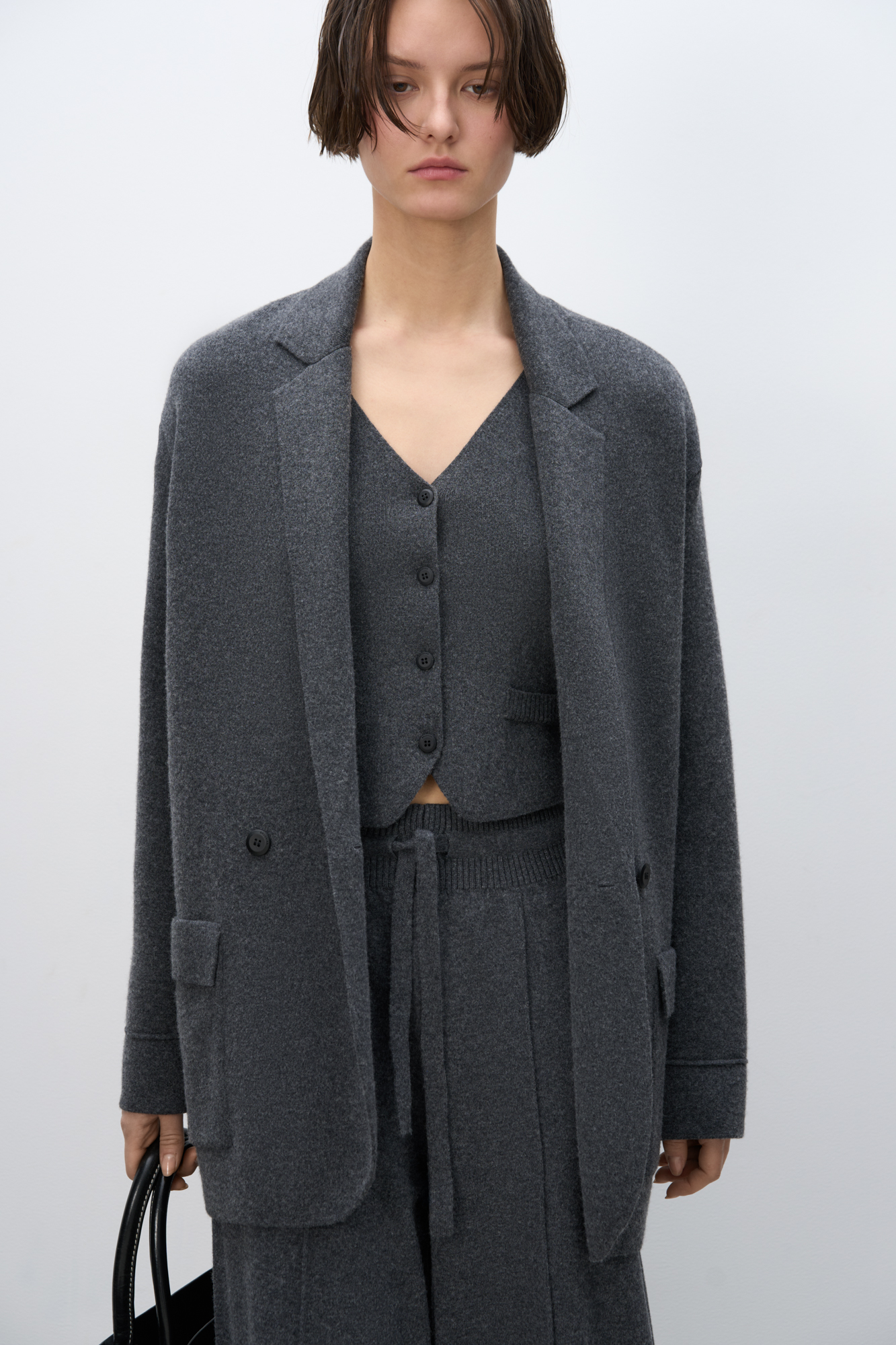 Трикотажный двубортный жакет из смесовой шерсти с добавлением кашемира. Модель прямого кроя, с прямоугольными лацканами и накладными карманами с клапанами спереди. Изделие без подкладки.
