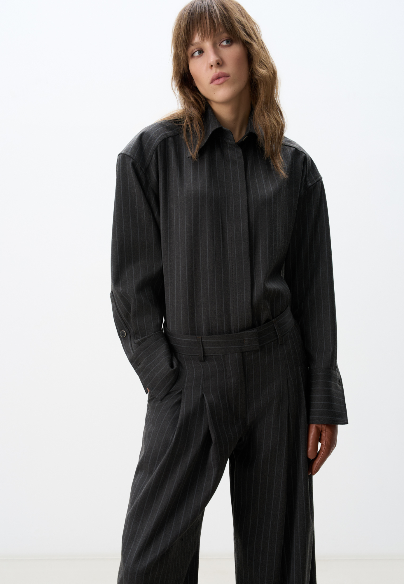 Рубашка из шерсти в полоску. Модель прямого кроя, с длинными рукавами, расклешенными манжетами, классическим отложным воротником и увеличенными плечами. Застежка на пуговицы под планкой.