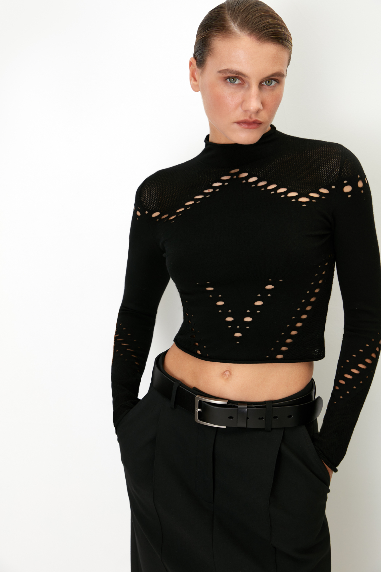 Трикотажная укороченная водолазка из тонкой эластичной вискозы. Модель облегающего силуэта, с длинными рукавами и невысоким воротником-стойкой. Изделие выполнено в комбинированной технике вязки, сочетающей гладь и сетку. Водолазка декорирована вырезами, создающими геометрический узор.<br />
