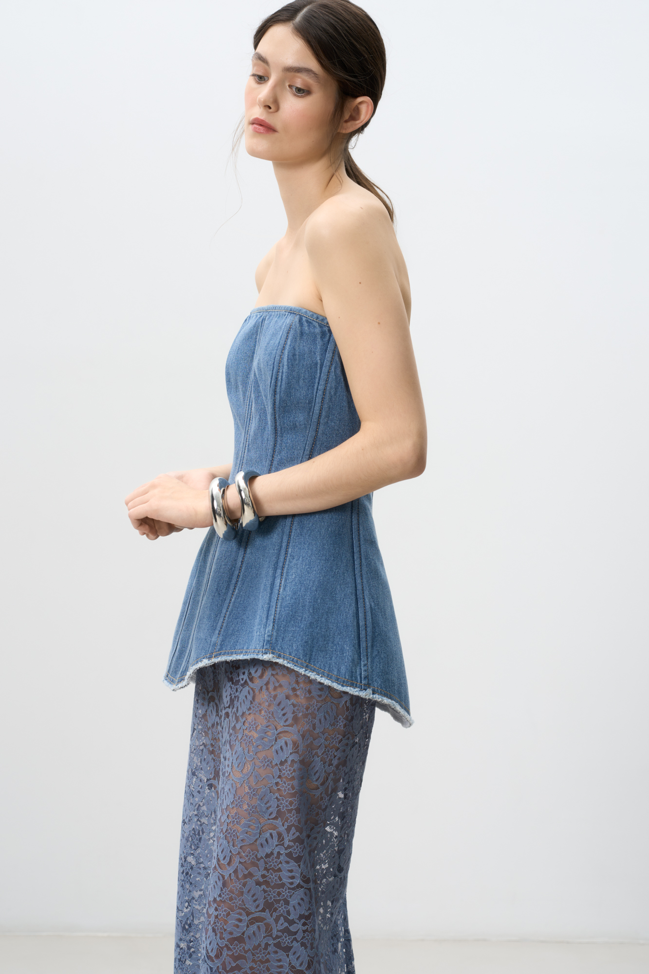 Джинсовый корсет из 100% хлопка. Модель с асимметричным низом, рельефными швами, контрастной стройчкой и застежкой на молнию на спине. Изделие на подкладке.