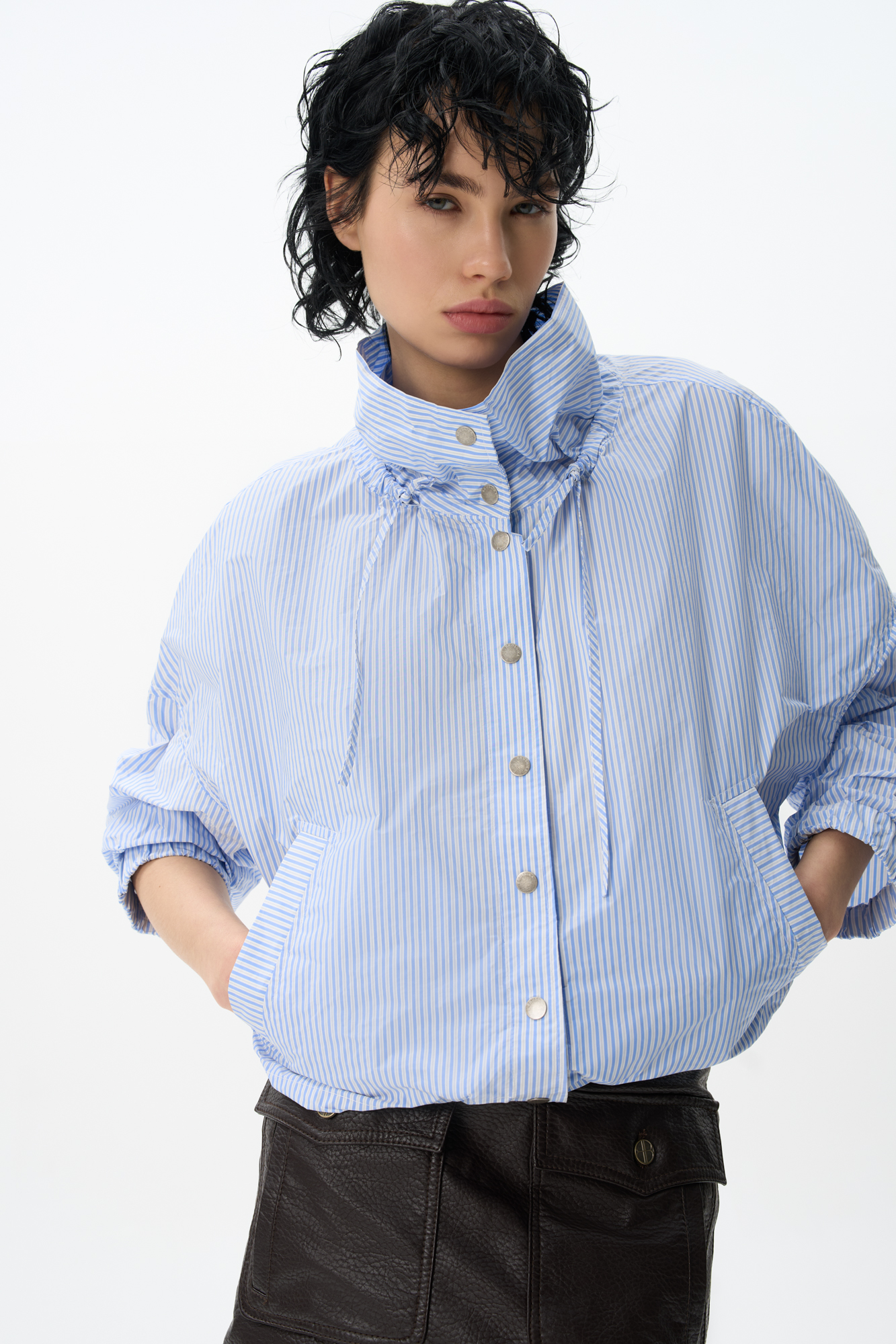 Ветровка, выполненная из полиэстера с принтом в полоску. Модель свободного силуэта с воротником-стойкой на кулиске, спущенной линией плеч и широкими рукавами. Застежка на металлические кнопки. Изделие выполнено без подкладки.