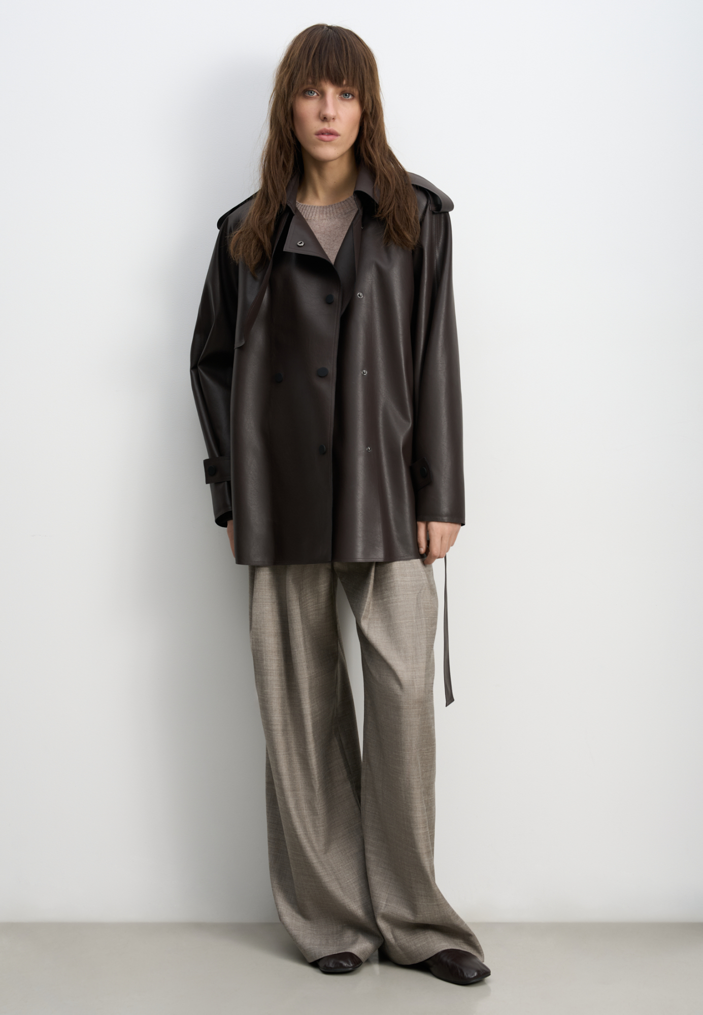 Тренч из двусторонней экокожи. Модель прямого кроя с широким отложным воротником и кокеткой. Изделие декорировано патами на плечах и манжетах рукавов. Два боковых кармана. Застежка на кнопки.