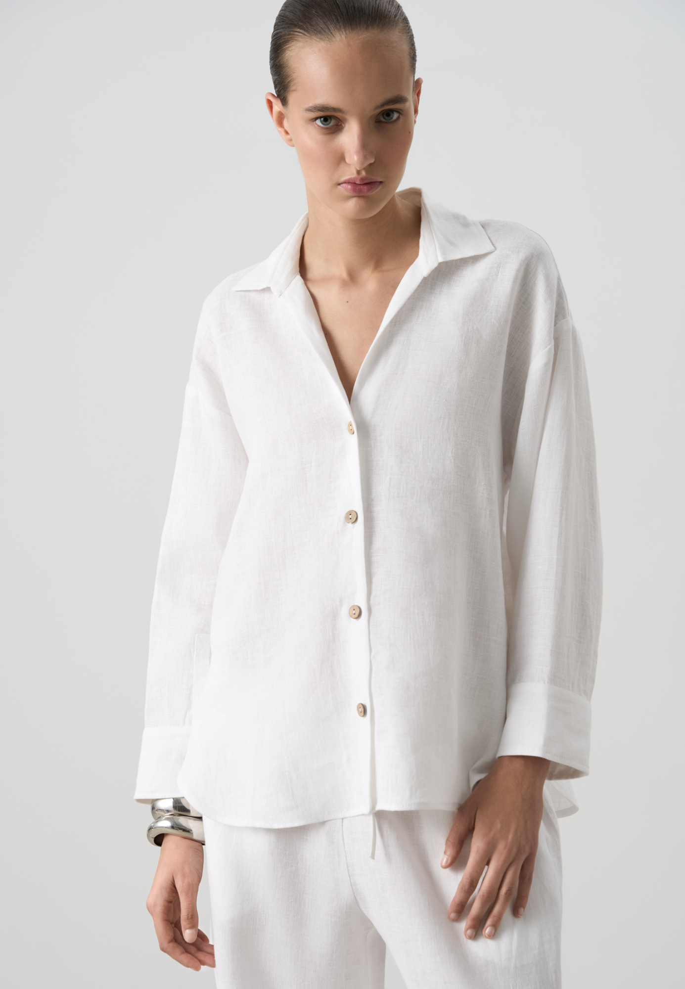Рубашка из 100% льна. Модель свободного кроя, с отложным воротником, V-образным вырезом, длинными рукавами с манжетами на пуговицах.
