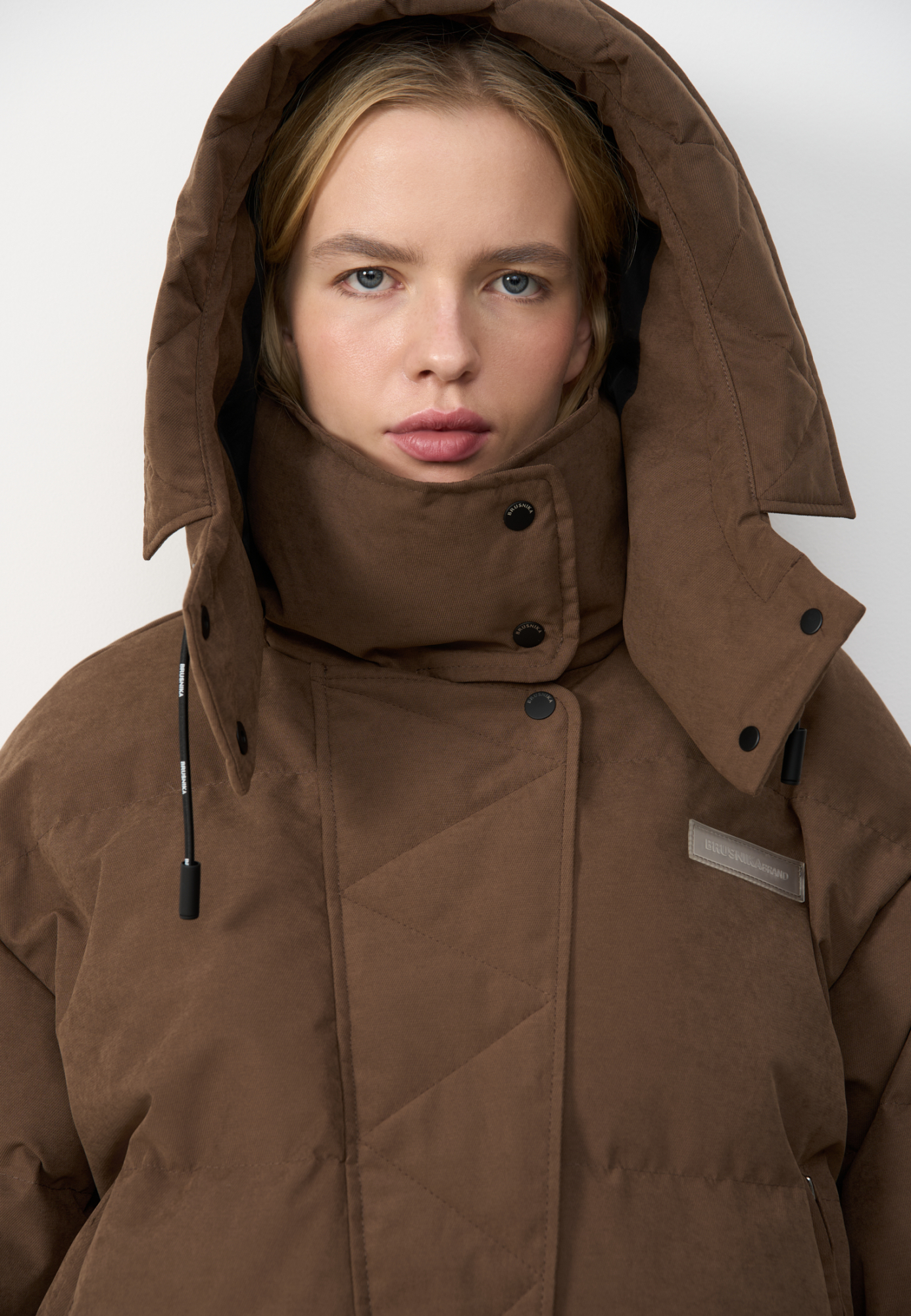 Утепленный пуховик с воротником-стойкой и капюшоном на молнии. Модель свободного силуэта с боковыми карманами, спущенным плечом и брендированным ярлыком на груди. Застежка на потайную молнию и кнопки. Наполнитель натуральный пух 90% перо 10%.