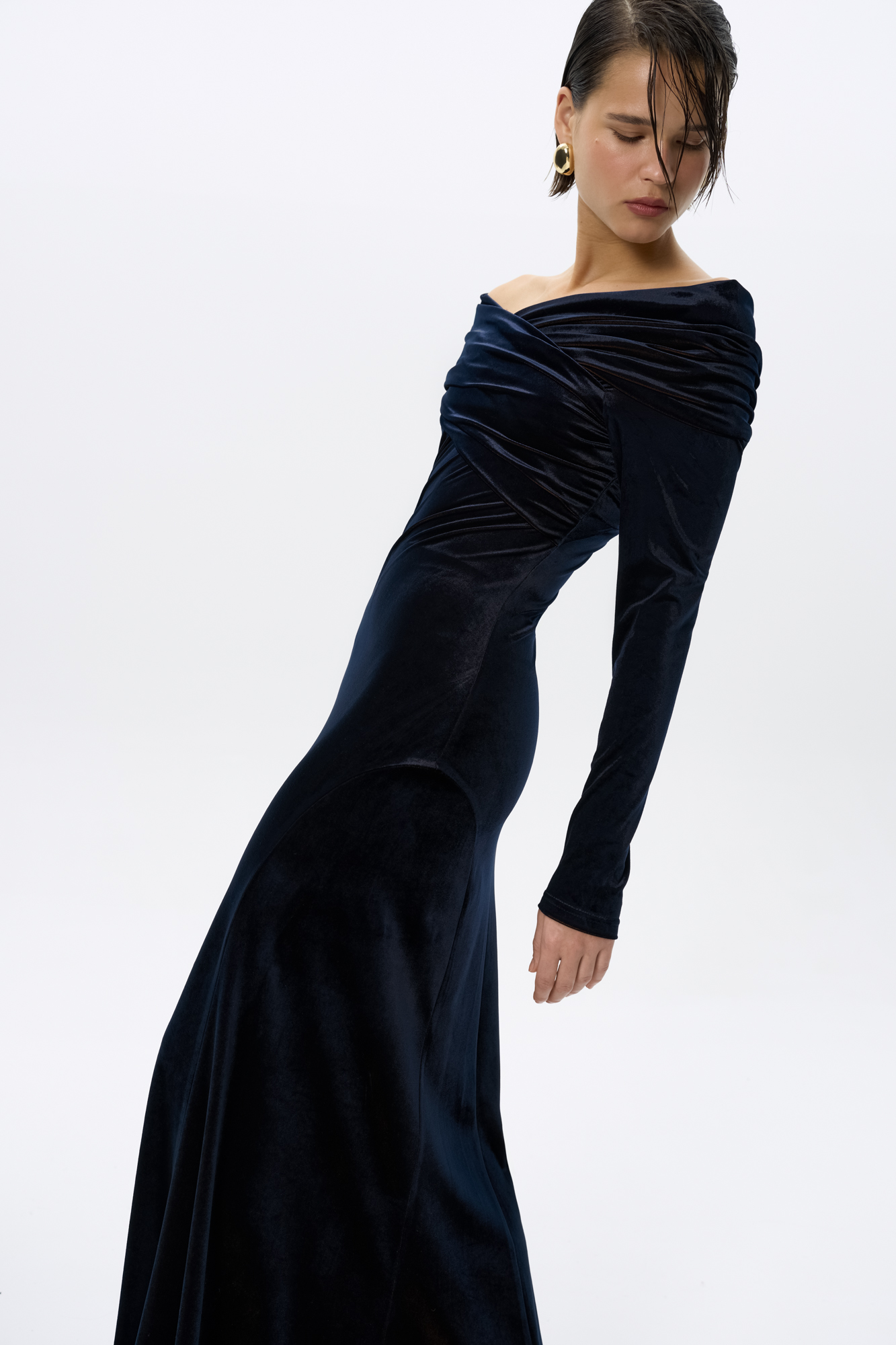 Платье из велюра длины макси. Модель приталенного силуэта с открытой линией плеч и длинными рукавами. Изделие декорировано драпировкой. Благодаря необычной текстуре ткани достигается эффект перелива цвета.
