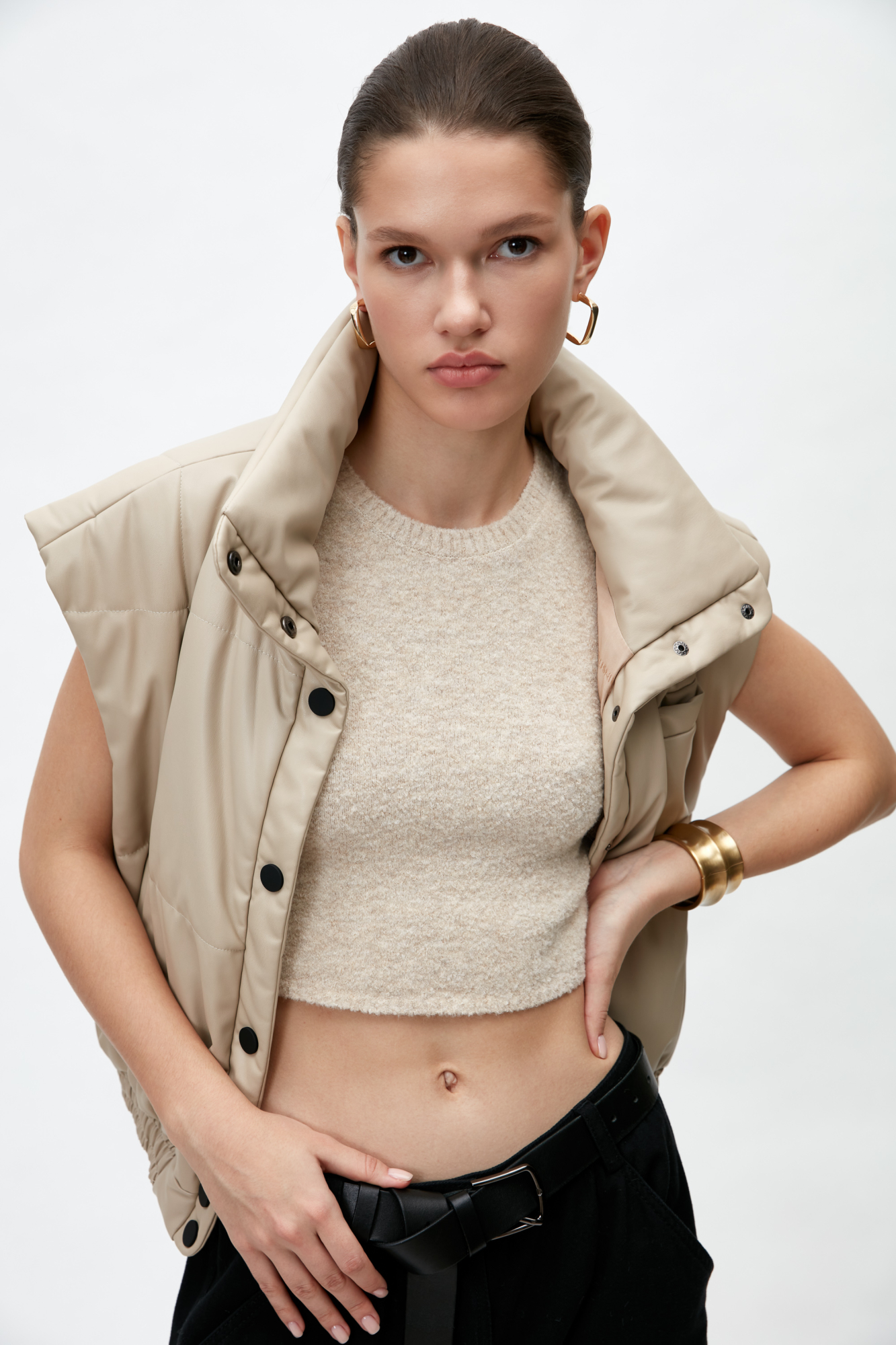 Жилет из экокожи. Модель приталенного силуэта с воротником-стойкой и боковыми карманами. Низ изделия на резинке, застежка на кнопки.