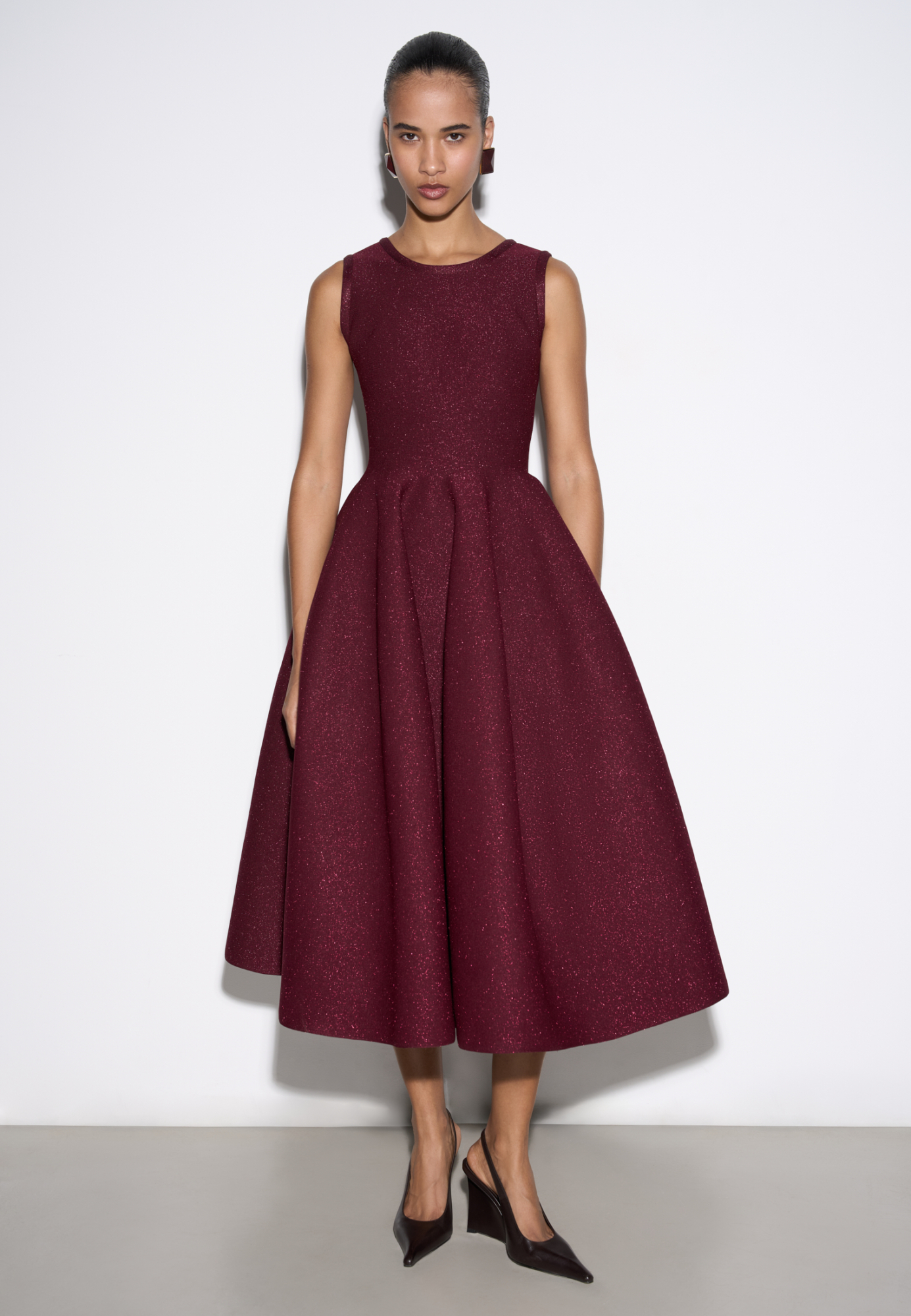 Трикотажное платье длины миди с люрексом. Модель по фигуре с юбкой, расклешенной от талии, без рукавов, на широких бретельках.