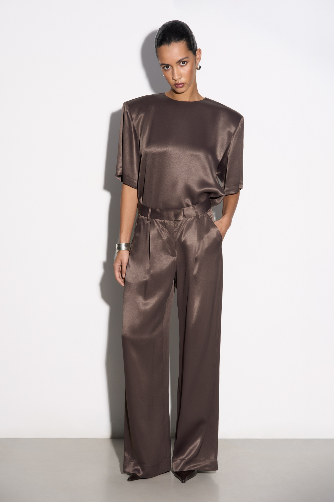 Атласные брюки из 100% вискозы. Модель прямого кроя со шлевками на поясе для ремня, карманами и застежкой на молнию, брючный крючок и пуговицу.