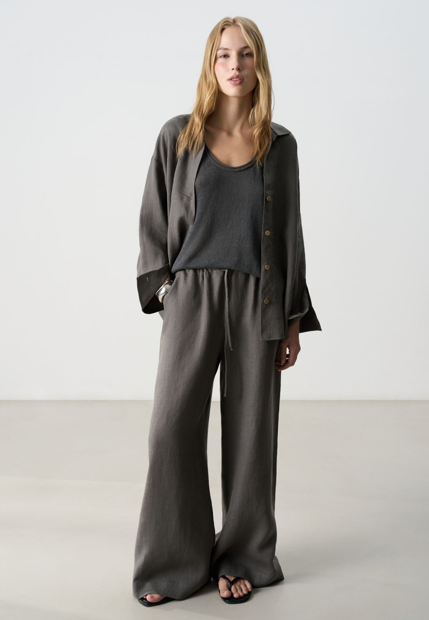 Широкие брюки из 100% льна. Модель свободного прямого кроя с врезными карманами по бокам. Изделие выполнено с поясом на узкой резинке, дополненным кулиской.