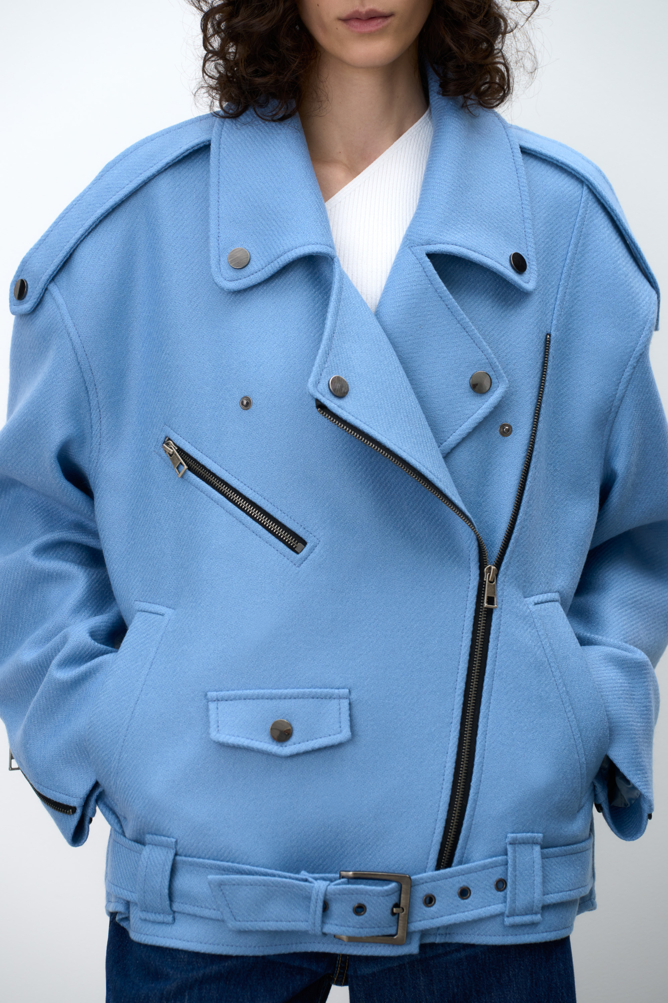 Жакет-косуха из смесовой шерсти. Модель свободного силуэта со спущенной линией плеч и косой застежкой. Изделие декорировано эполетами на плечах, широким поясом с пряжкой на талии, боковыми и нагрудным карманом. Изделие на подкладке.