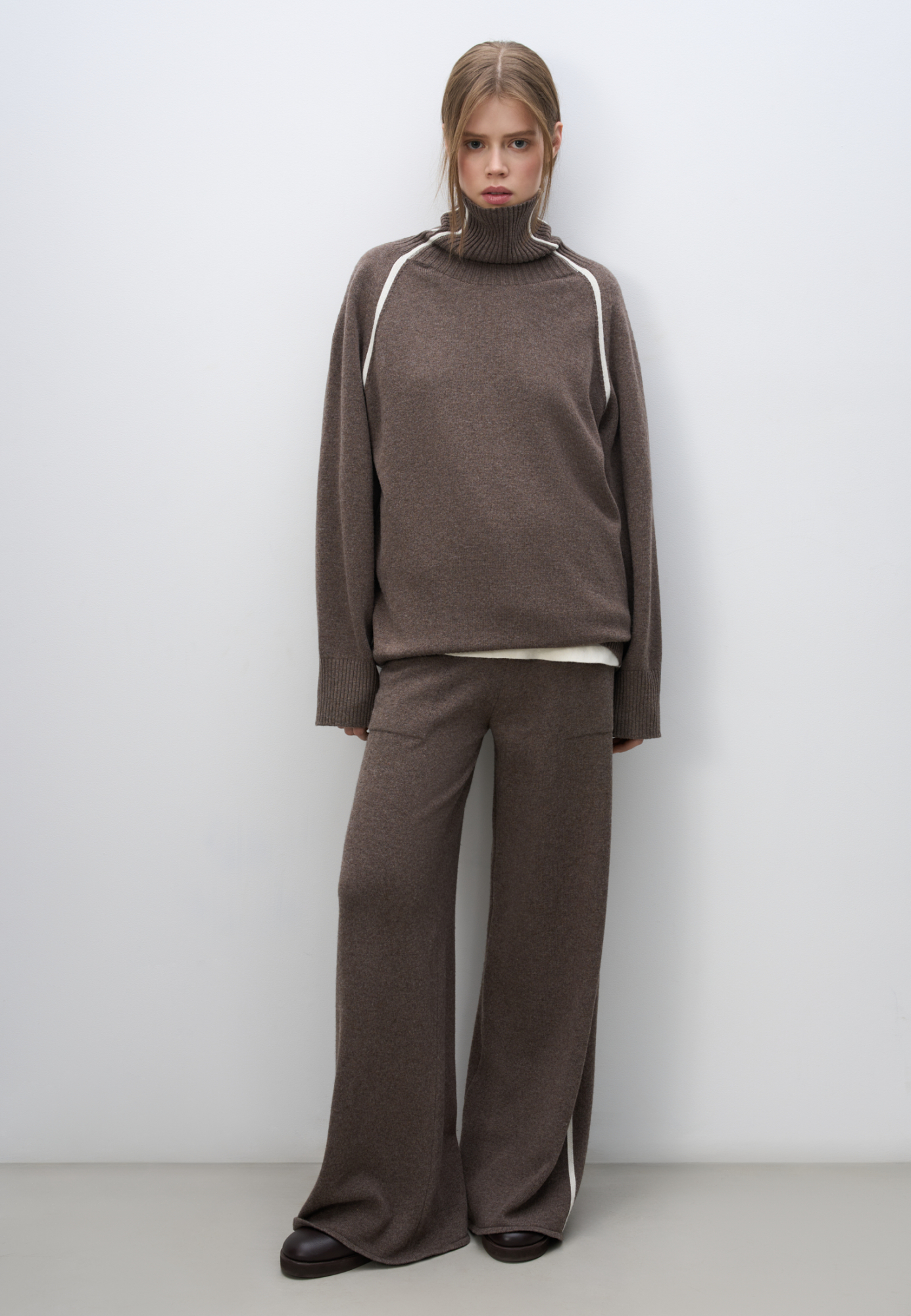 Трикотажные брюки из кашемира и шерсти. Модель свободного силуэта со средней посадкой, боковыми вывязанными карманами и эластичным поясом на кулиске. Изделие декорировано лампасами контрастного цвета.