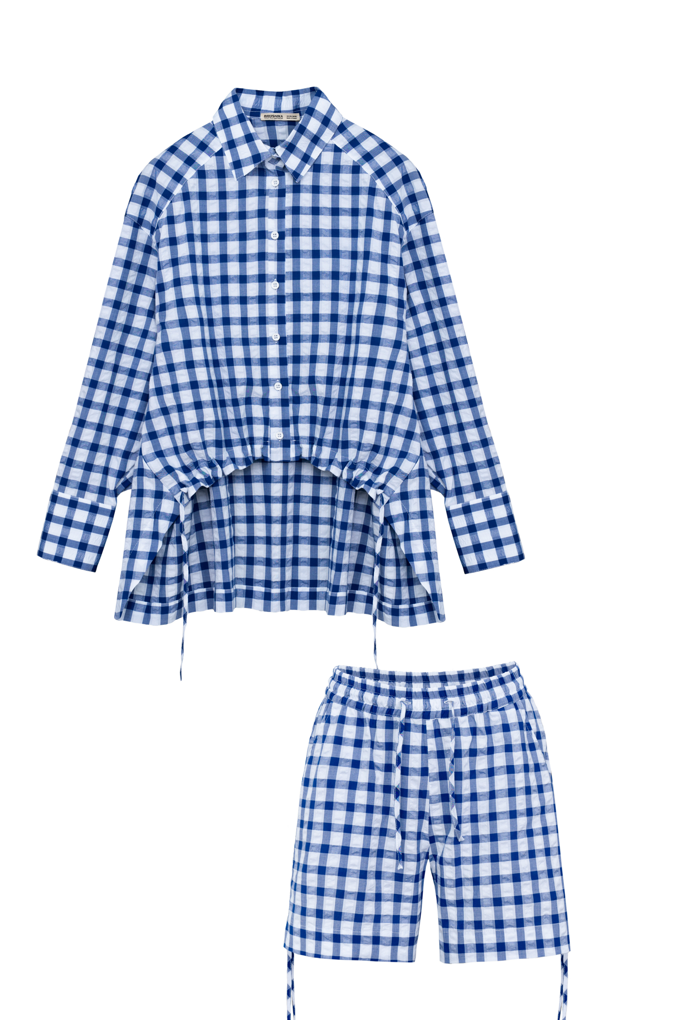 Принтованный костюм из 100% хлопка, состоящий из рубашки и шорт. Рубашка свободного кроя, с длинными рукавами, классическим отложным воротником и кулиской по низу изделия. Короткие шорты с карманами, широким поясом на кулиске и завязками по бокам.