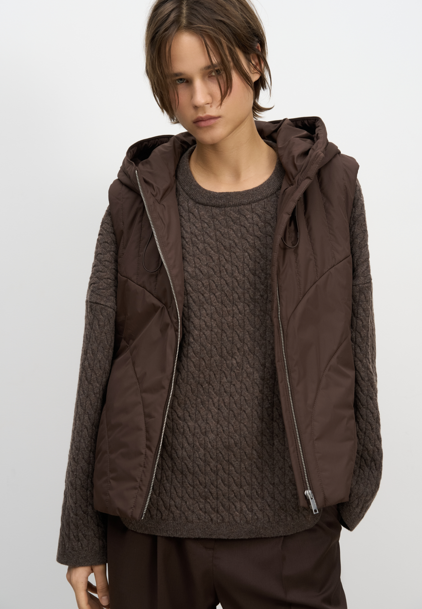 Жилет на синтепоне с капюшоном. Модель свободного силуэта с боковыми карманами. Капюшон регулируется кулиской. Застежка на молнию. На подкладке. 