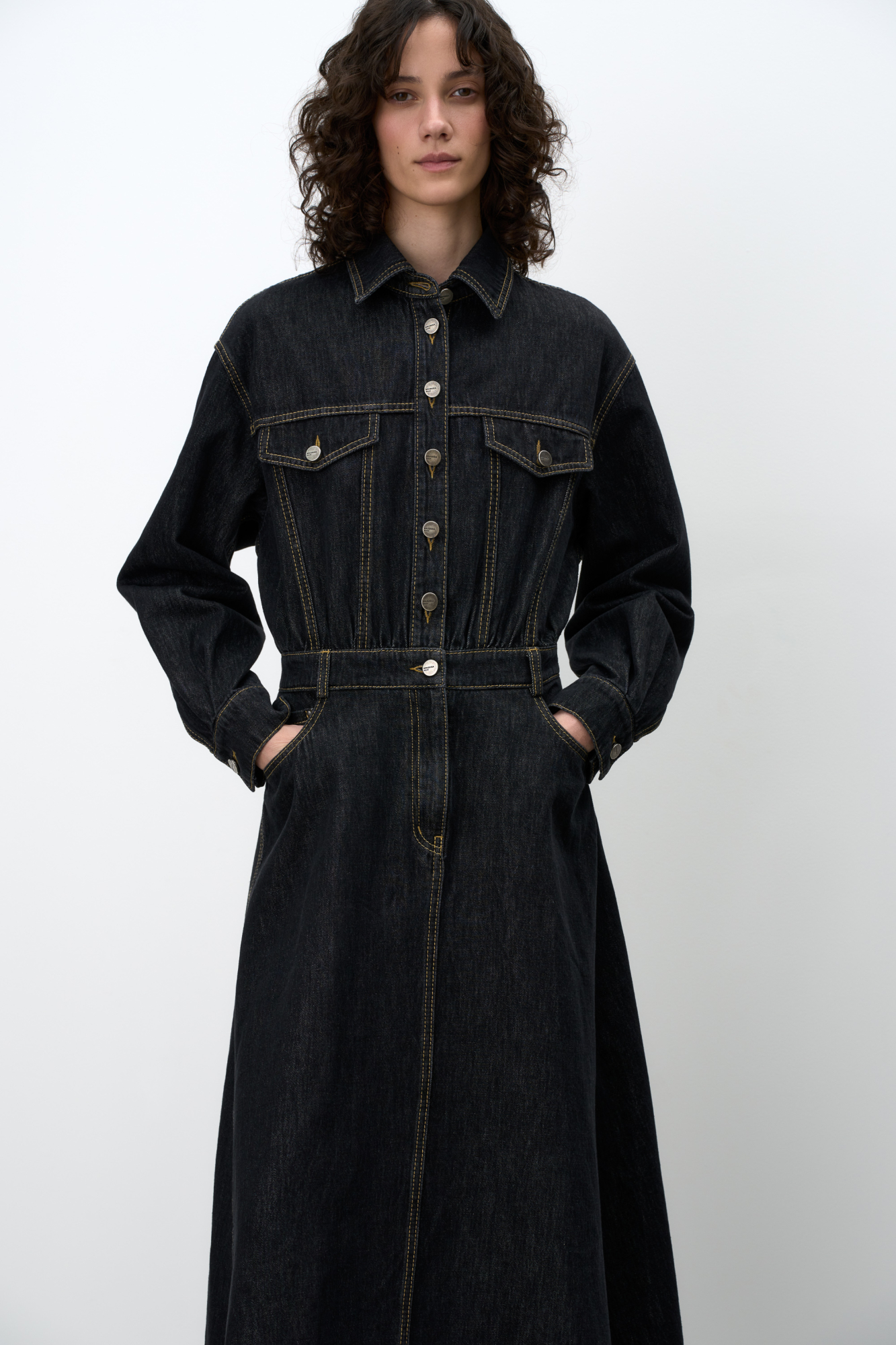 Джинсовое платье из 100% хлопка с длинным рукавом. Модель свободного силуэта с карманами на груди. Застежка на пуговицы.