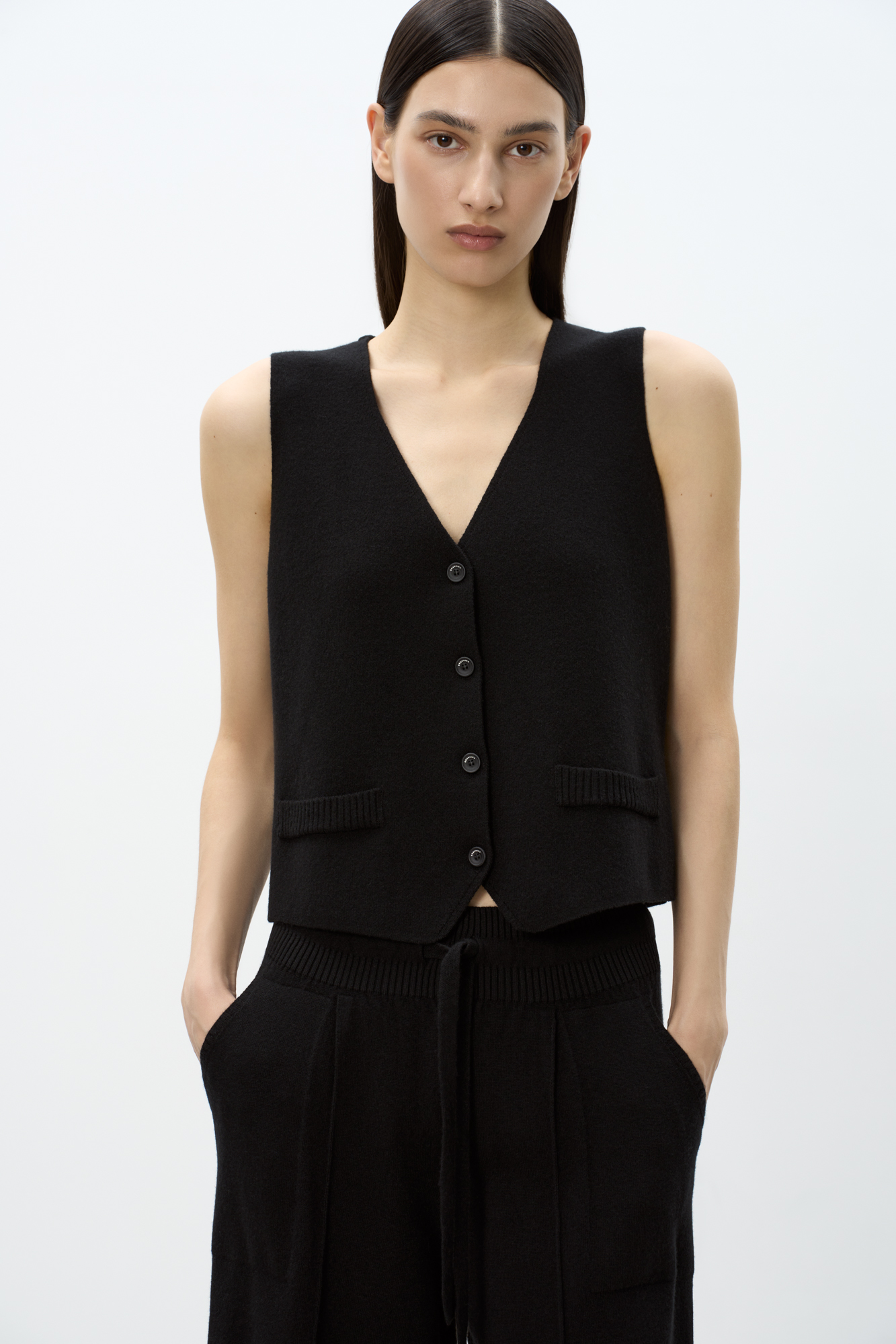 Трикотажный жилет из смесовой шерсти с кашемиром. Модель прямого кроя с V-образным вырезом и застежкой на пуговицы. Имитация карманов. Без подкладки.