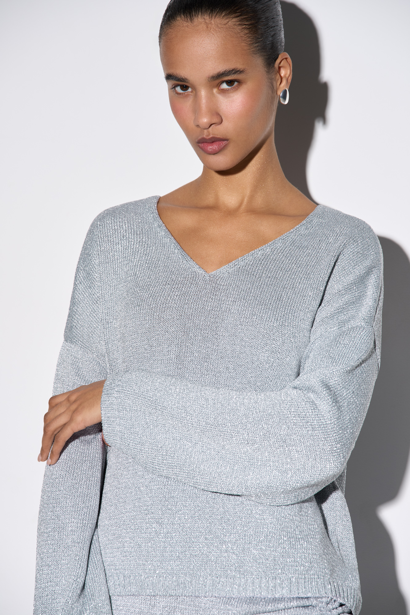 Джемпер из вискозы с добавлением люрекса. Модель свободного силуэта, со спущенной линией плеч и V-образным вырезом. Манжеты рукавов и низ изделия выполнены в рубчик.&nbsp;&nbsp;