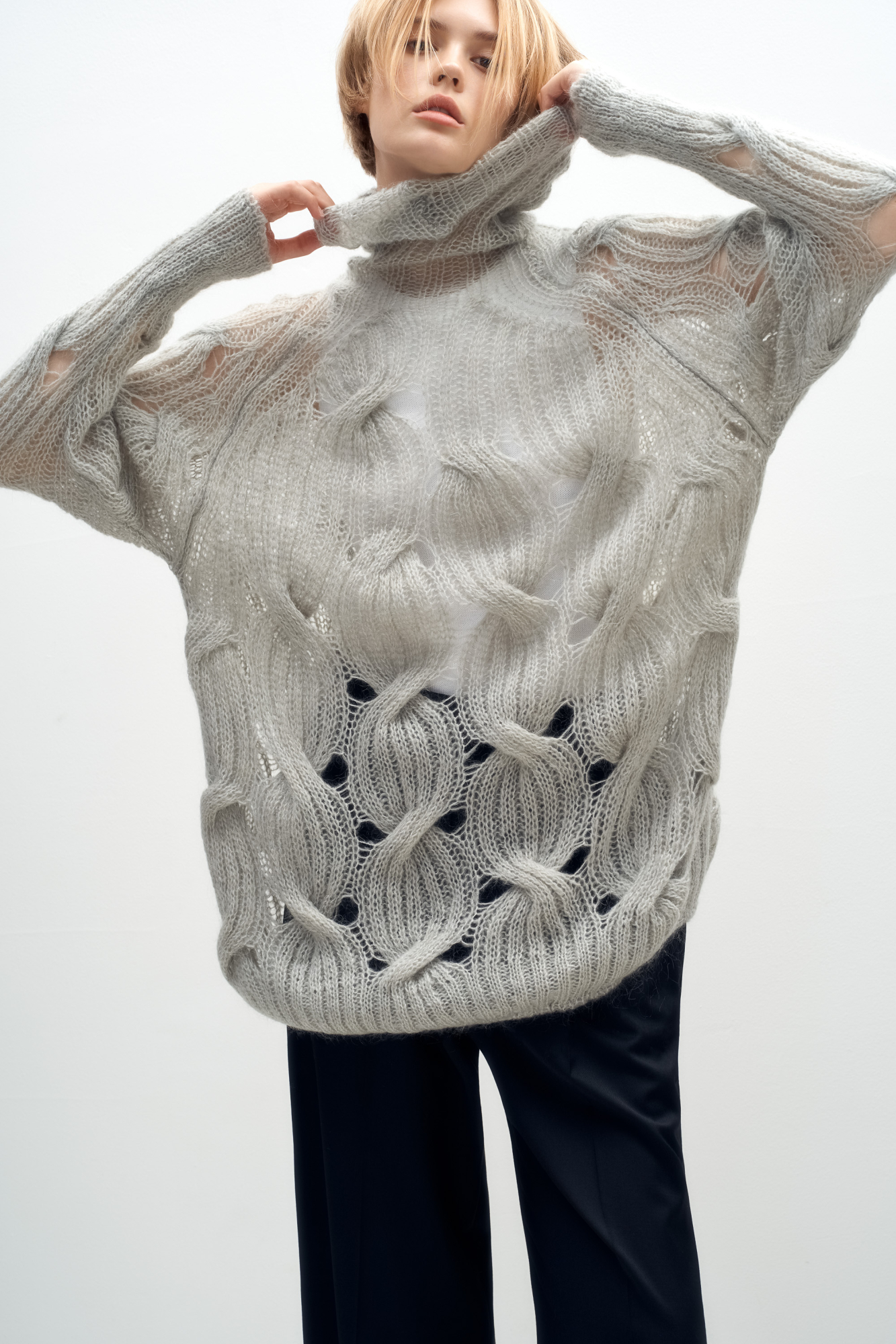 Объемный удлиненный джемпер с мохером, вязка выполнена крупными косами. Высокий ворот под горло. Манжеты рукавов и низ изделия на резинке. 