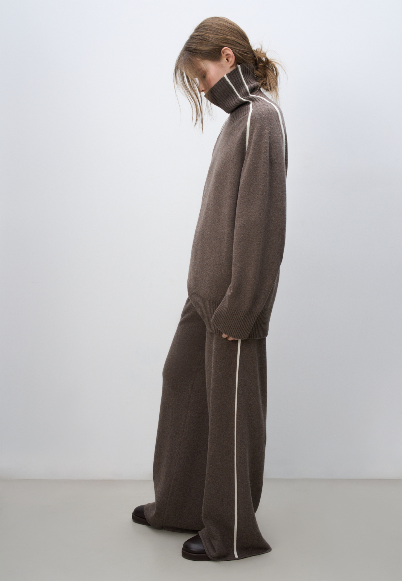 Трикотажные брюки из кашемира и шерсти. Модель свободного силуэта со средней посадкой, боковыми вывязанными карманами и эластичным поясом на кулиске. Изделие декорировано лампасами контрастного цвета.