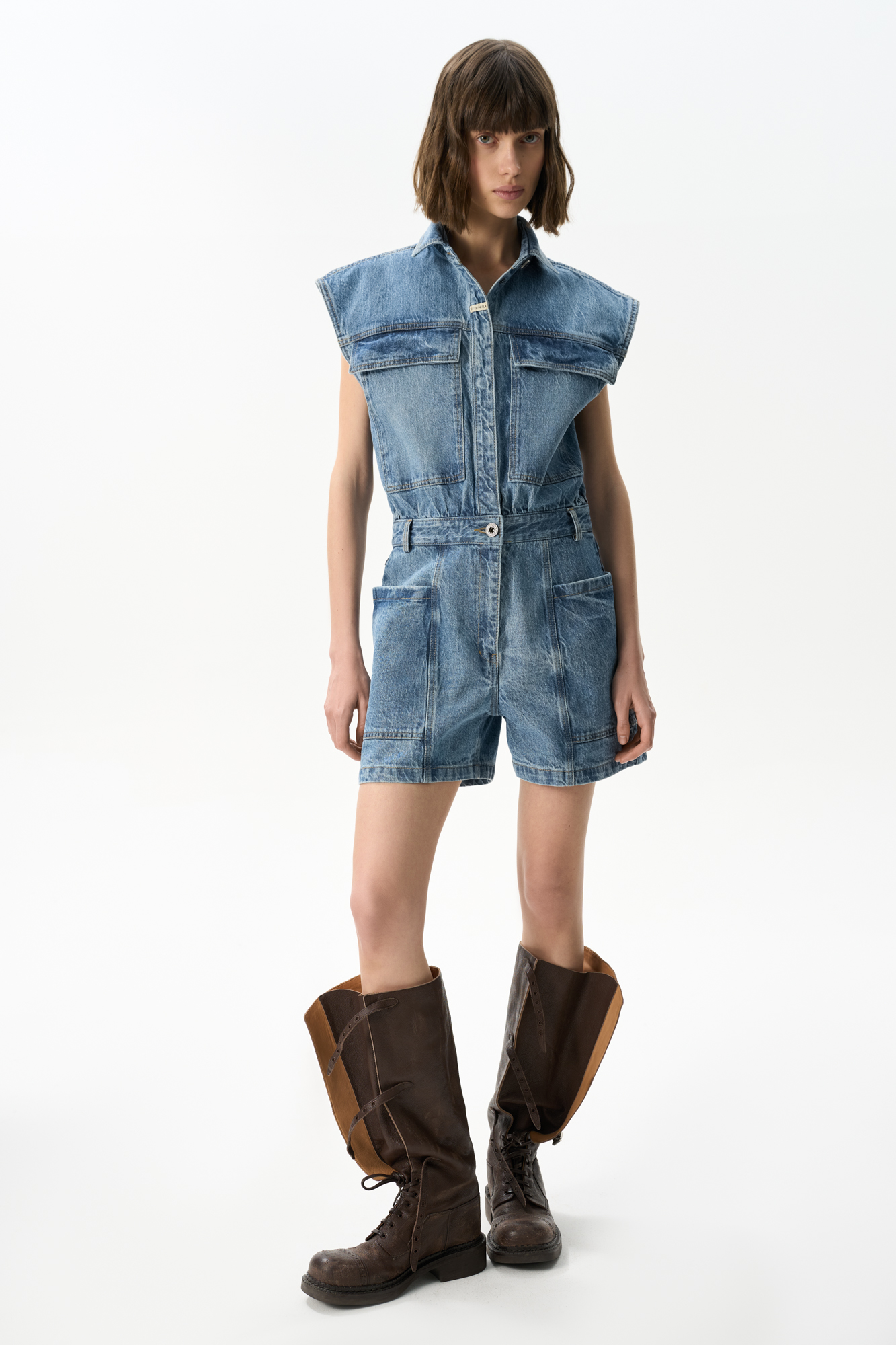 Джинсовый комбинезон из 100% хлопка. Модель с рубашечным верхом и шортами. Изделие с классическим отложным воротником, короткими рукавами-крылышками и застежкой на металлические пуговицы, шлевками на поясе для ремня и большими накладными карманами.