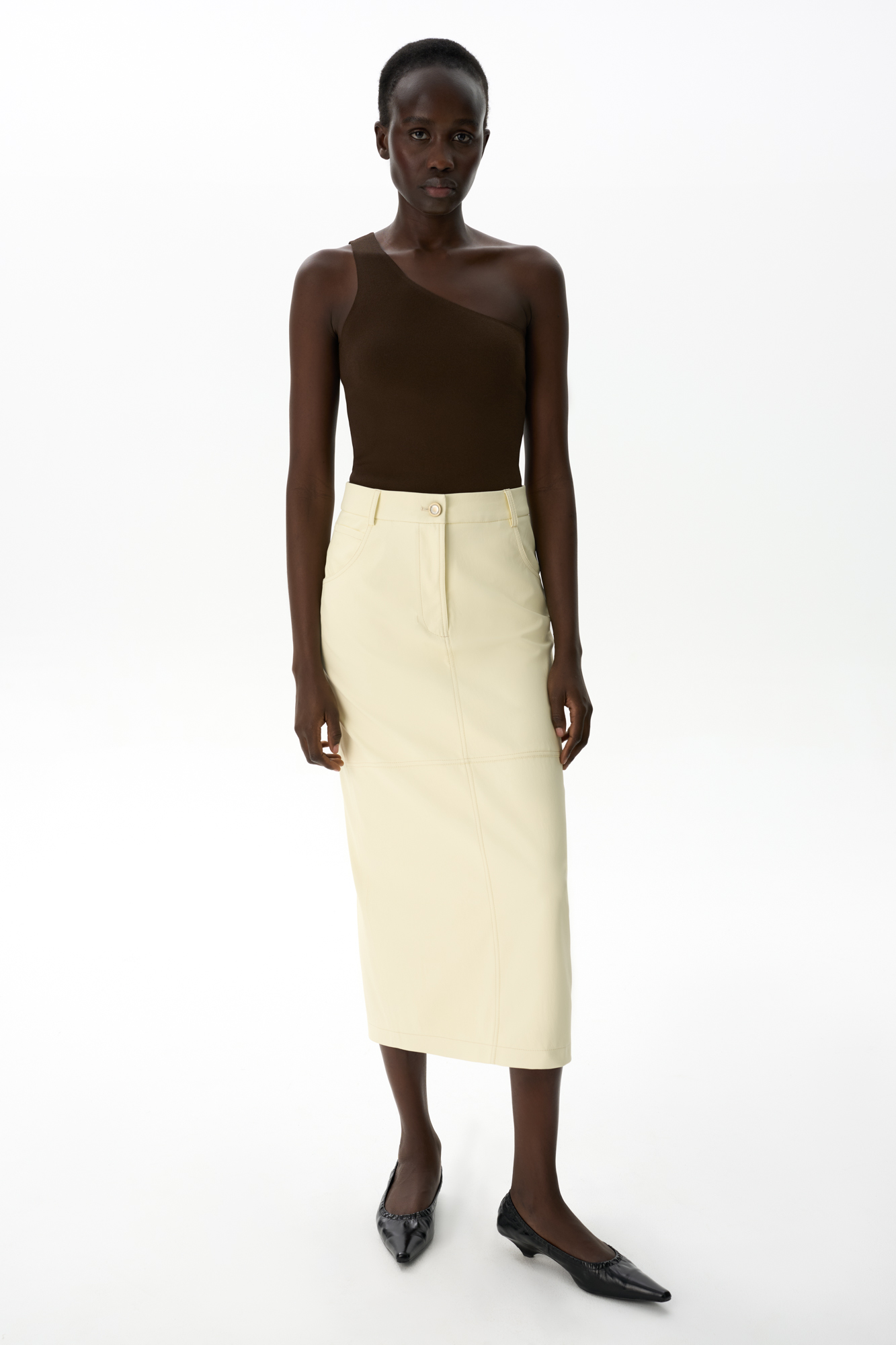 Юбка длины миди из мягкой двусторонней экокожи. Модель прямого кроя, с разрезом сзади, карманами и шлевками на поясе для ремня. Застежка на пуговицу и молнию.