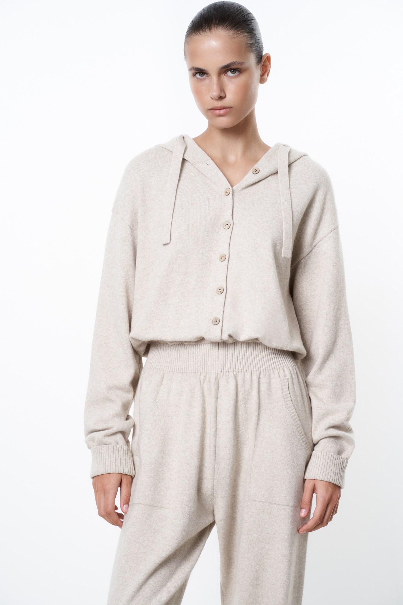 Трикотажный комбинезон из шерсти и кашемира, состоящий из худи и брюк. Худи с капюшоном и застежкой на пуговицы, брюки с широким эластичным поясом, боковыми карманами и манжетами на резинке.