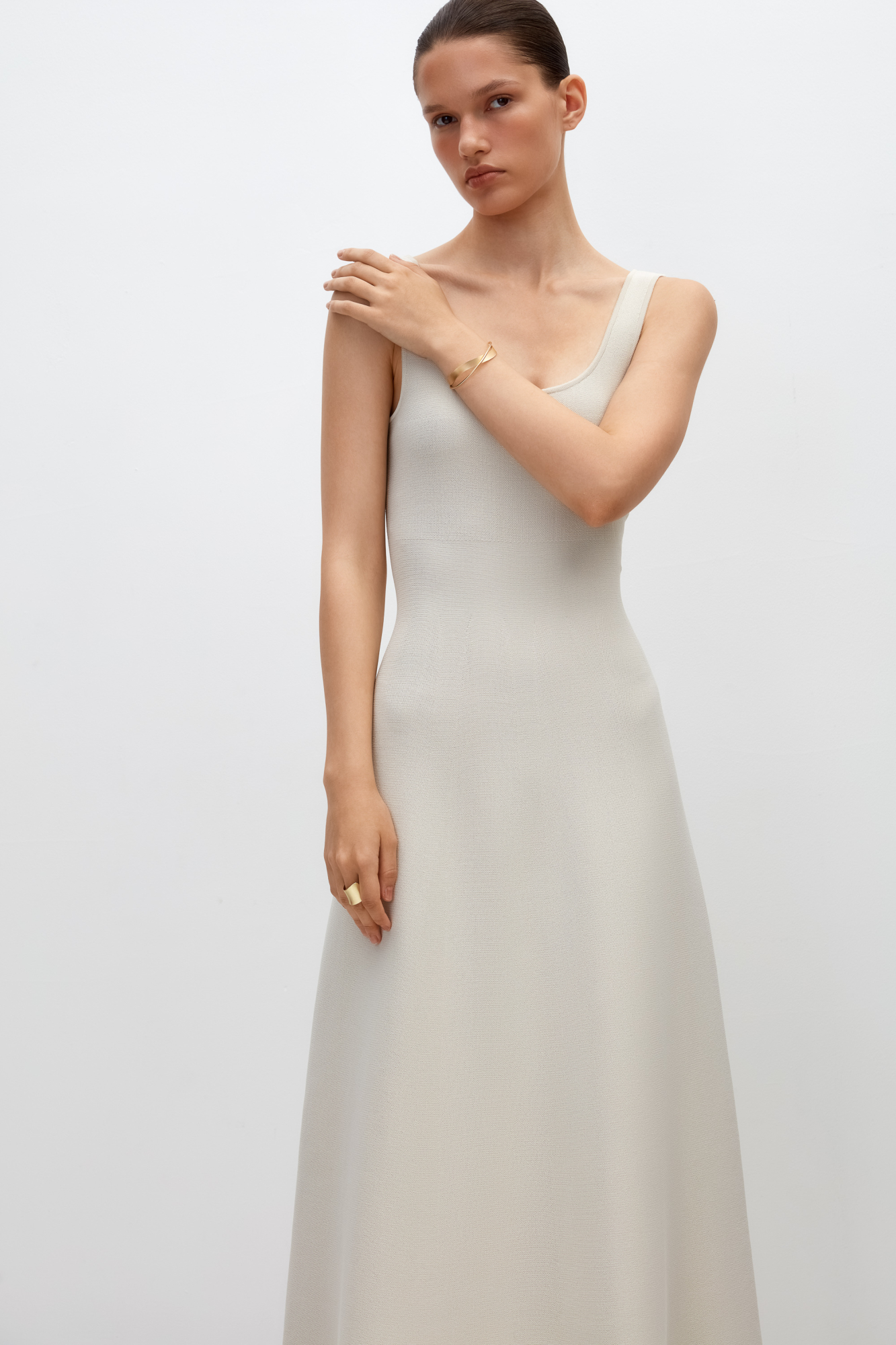 Трикотажное платье длины миди из плотной вискозы. Модель без рукавов, на широких бретелях и юбкой А-силуэта. Застежка на молнию сзади.