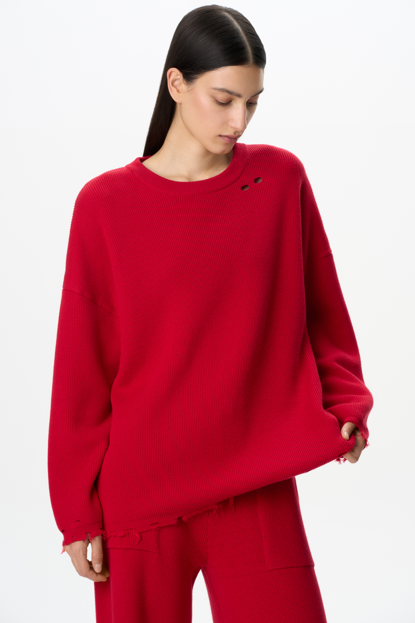 Трикотажный джемпер из хлопка с добавлением вискоза. Модель свободного силуэта со спущенной линией плеча и круглым вырезом горловины. Изделие декорировано имитацией драни и необработанным краем.